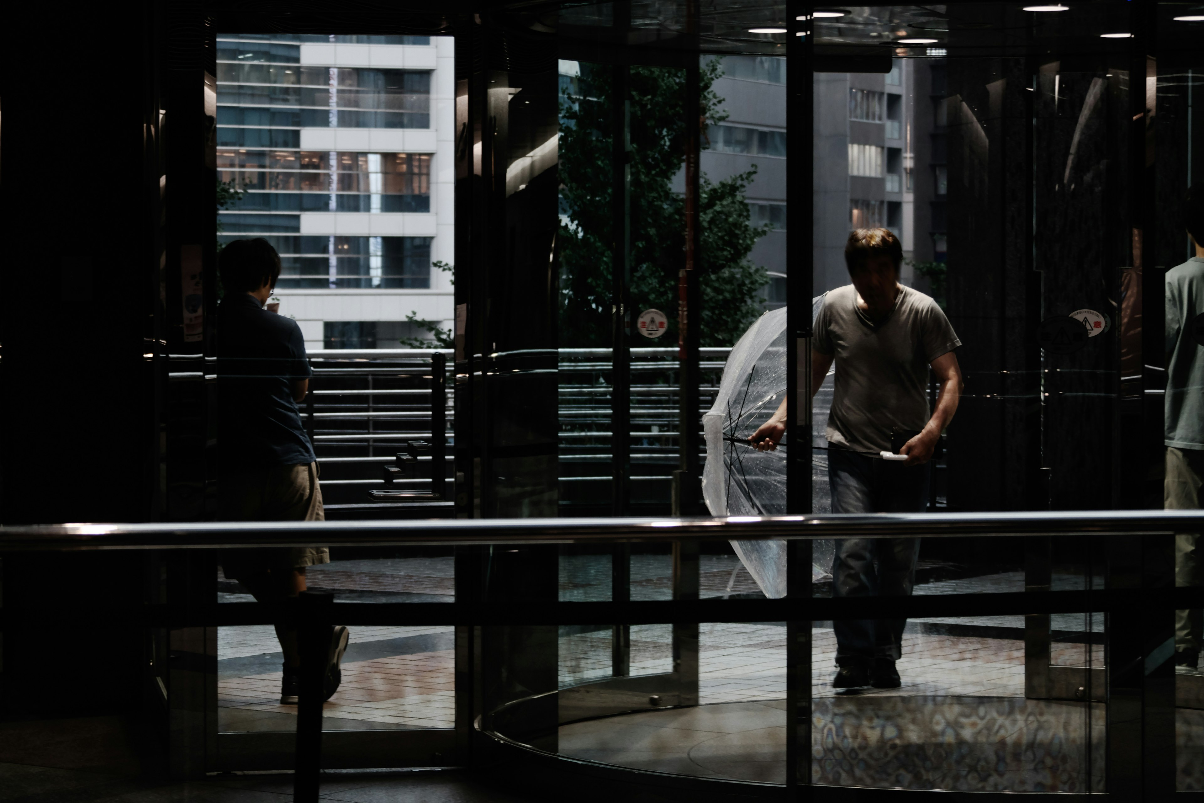 Silhouettes de personnes passant par une porte tournante avec un bâtiment en arrière-plan