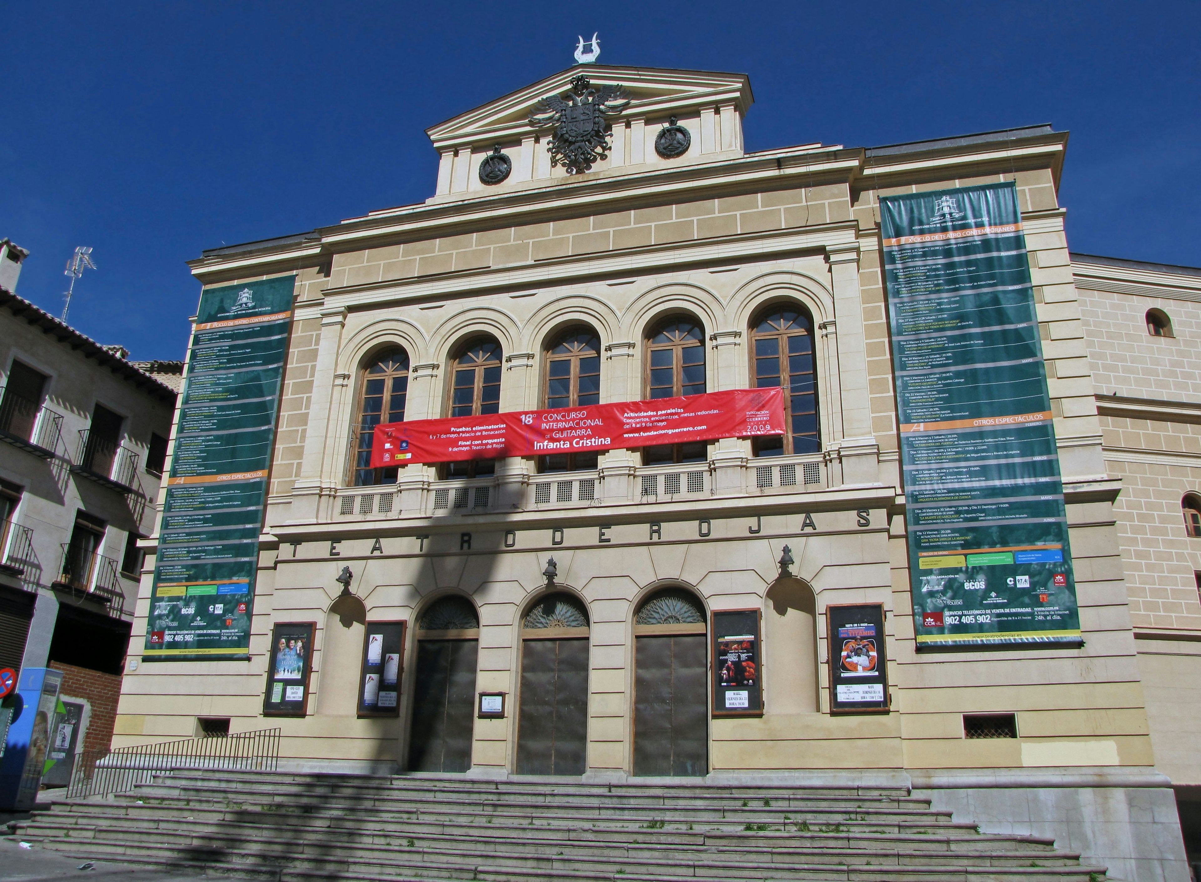 Fachada de un teatro histórico con pancartas rojas