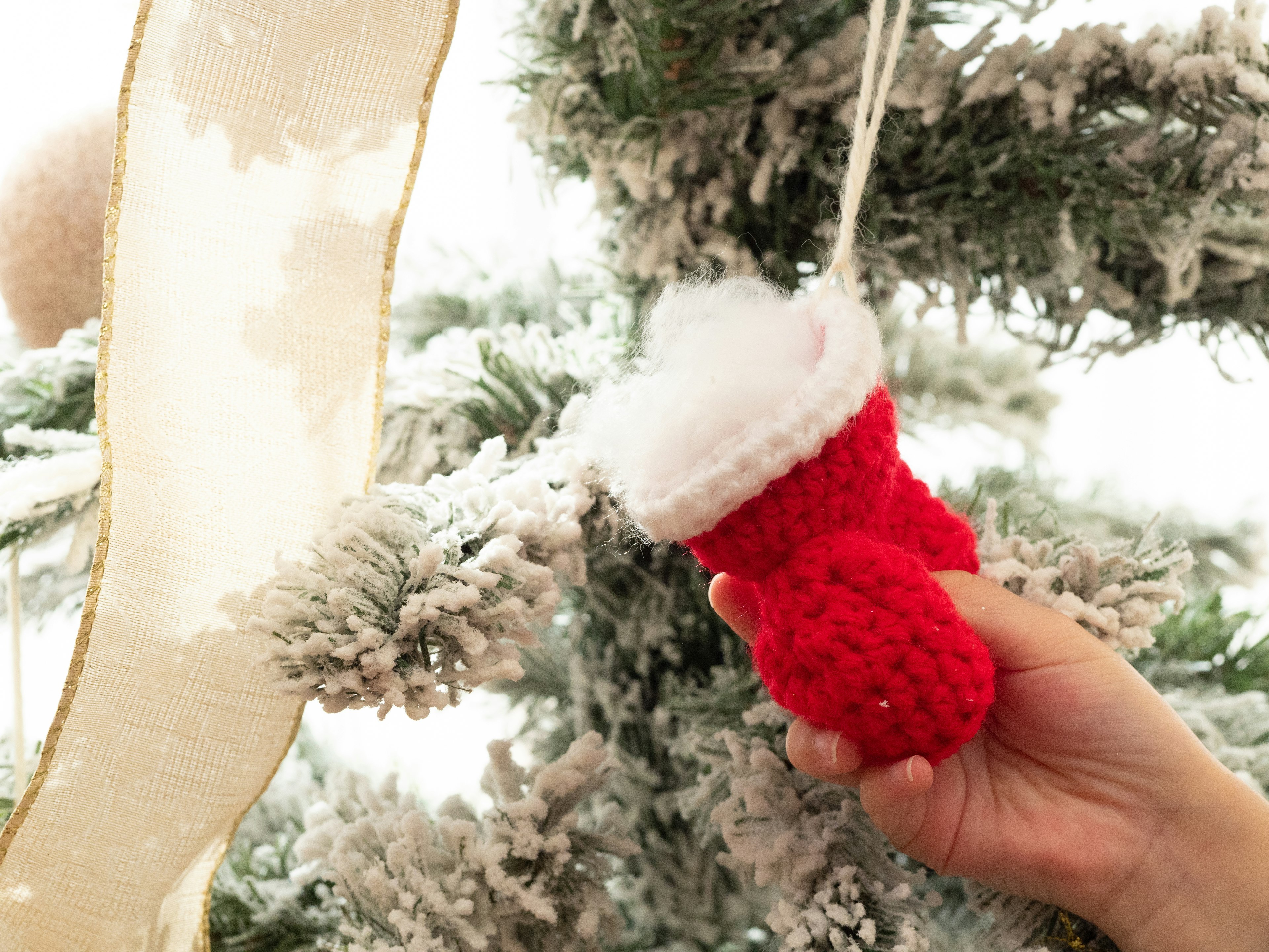 Mano che tiene un ornamento di calza di Natale mini rossa