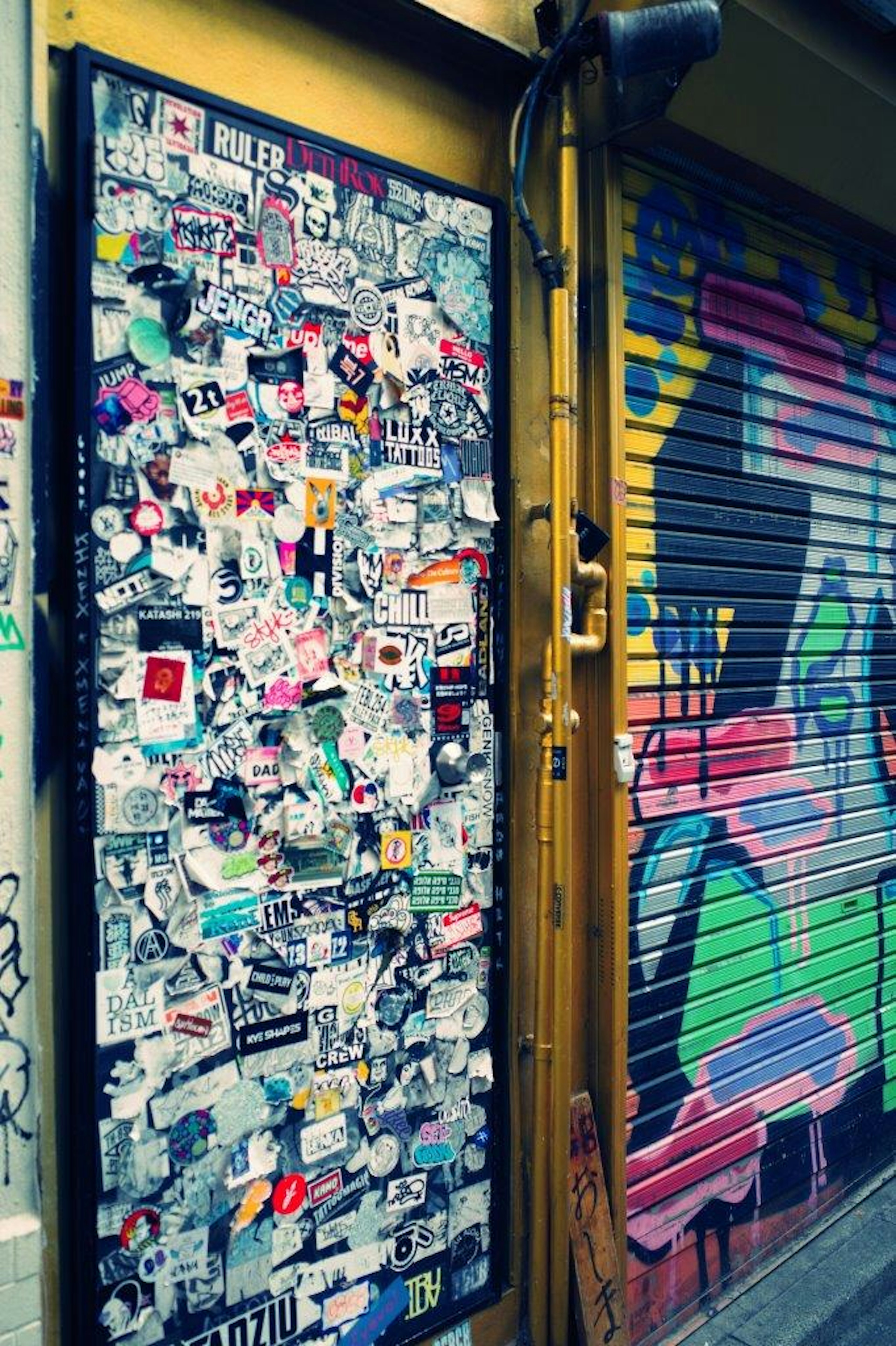 Image of a wall covered with colorful graffiti and stickers