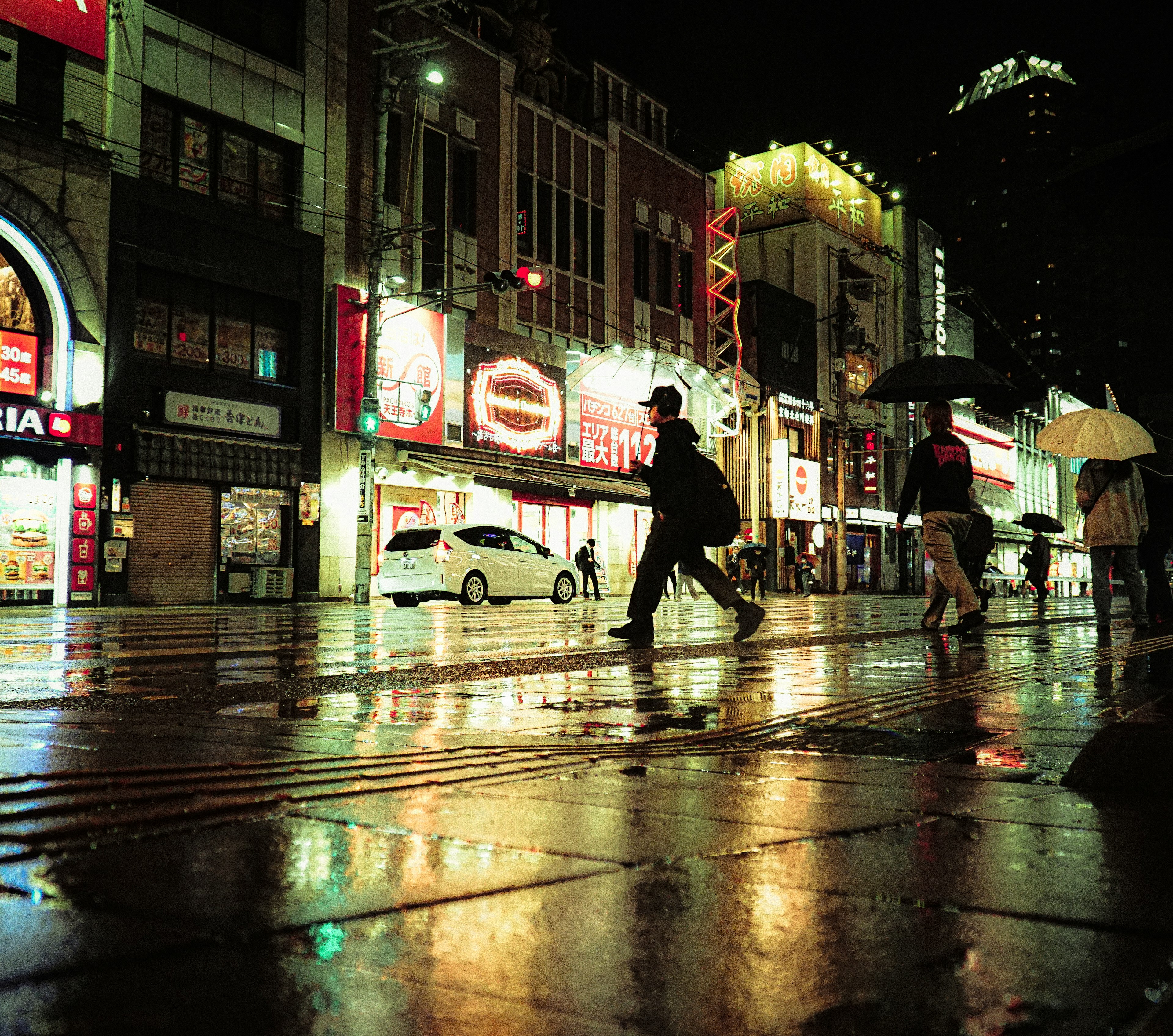 City street at night with neon lights and pedestrians walking on wet pavement