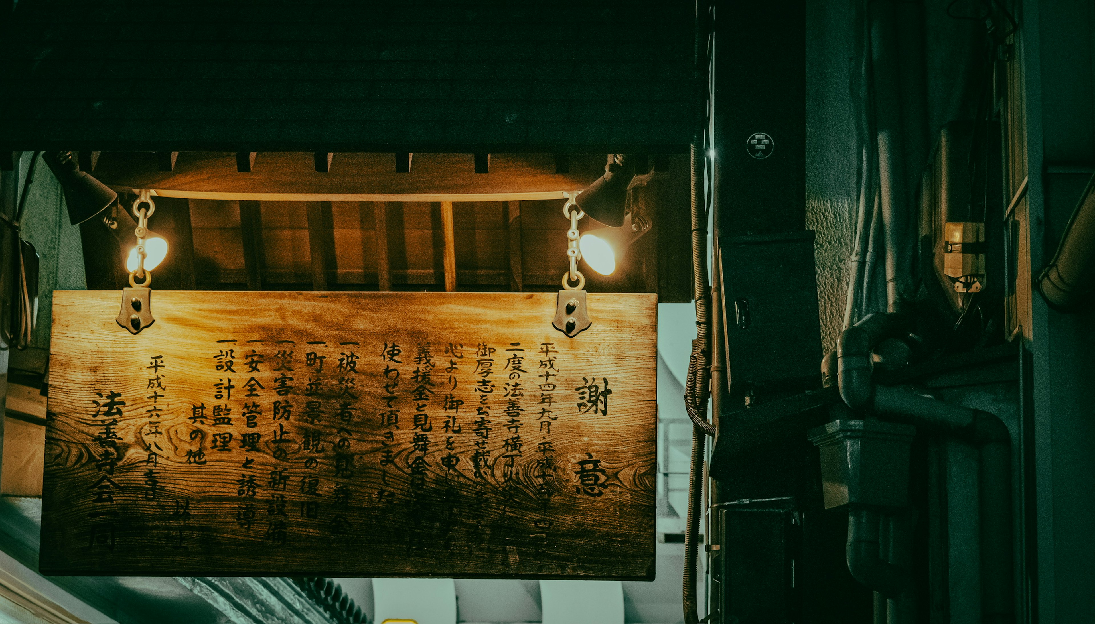 Wooden sign with kanji characters in a nighttime street scene