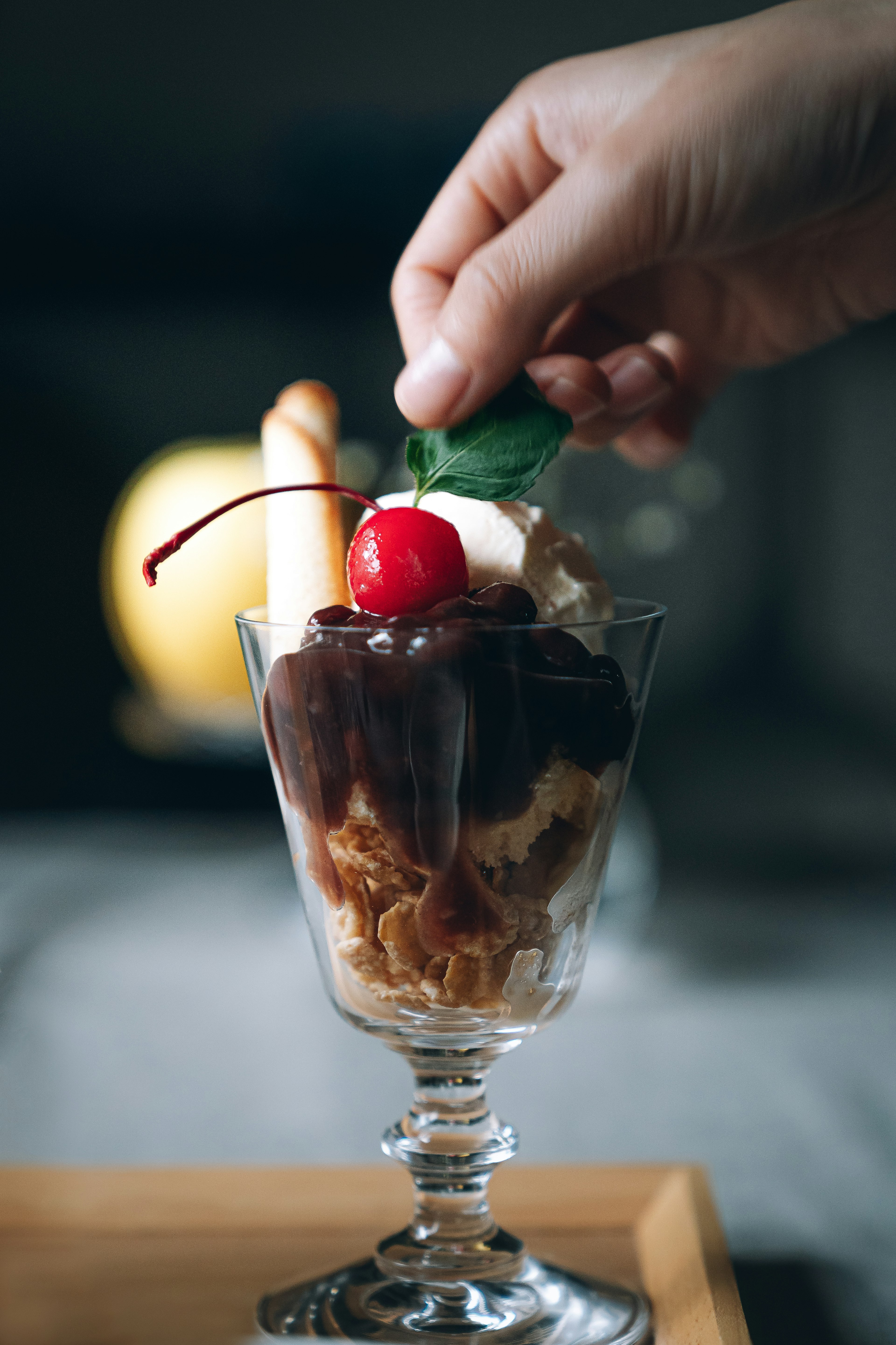 Mano añadiendo un topping a un parfait de helado