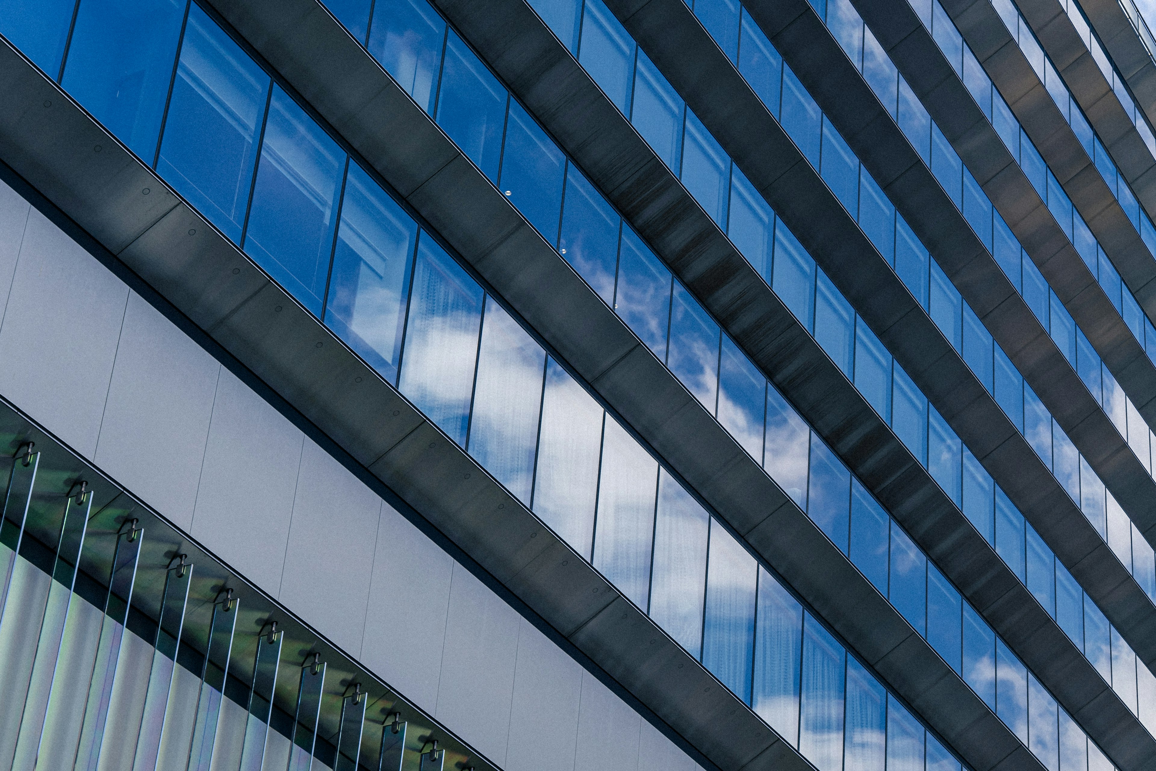 Moderne Glasfassade eines Wolkenkratzers, die den blauen Himmel und die Wolken reflektiert