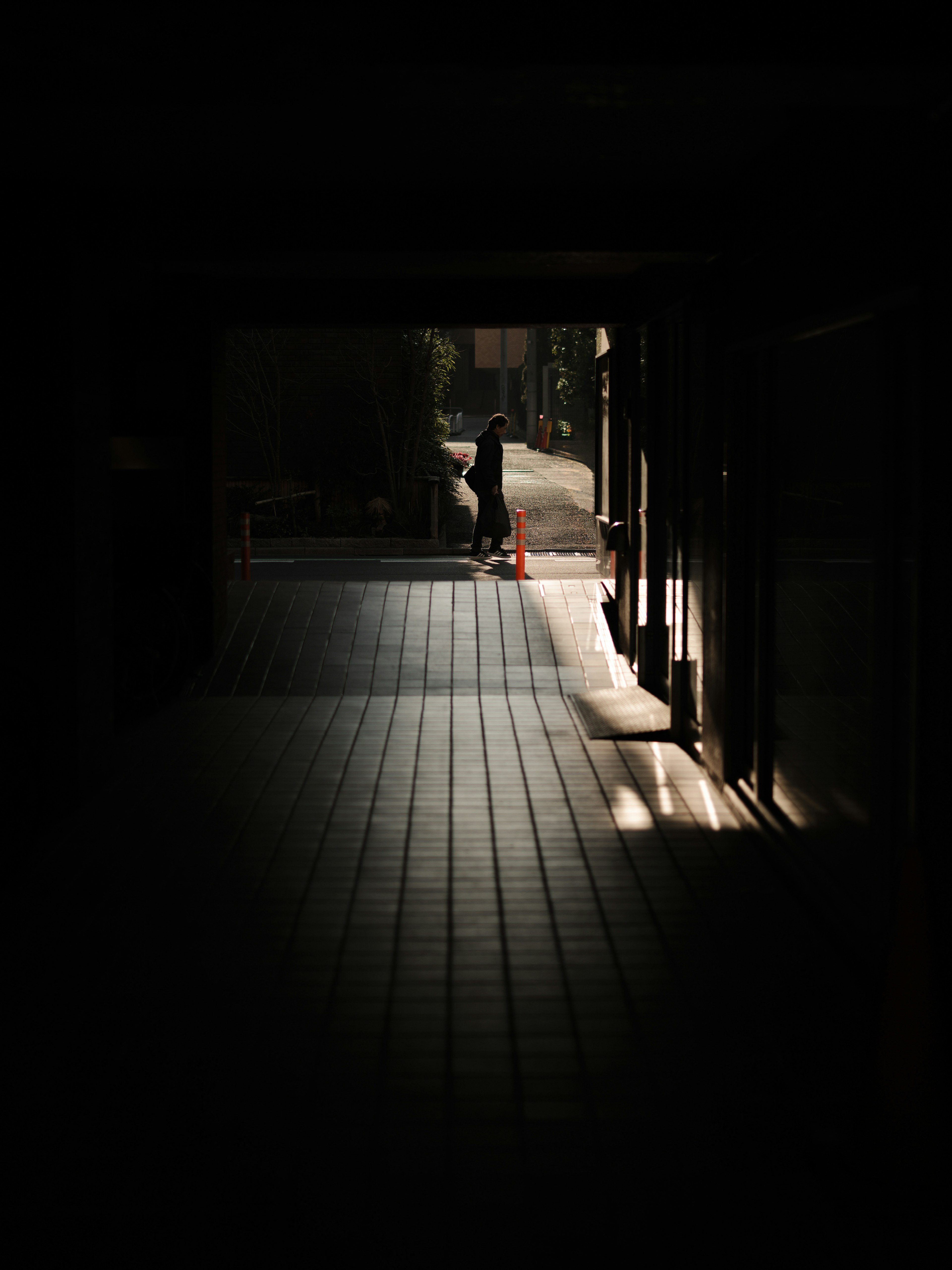 Silhouette einer Person in einem dunklen Flur mit Lichtkontrast