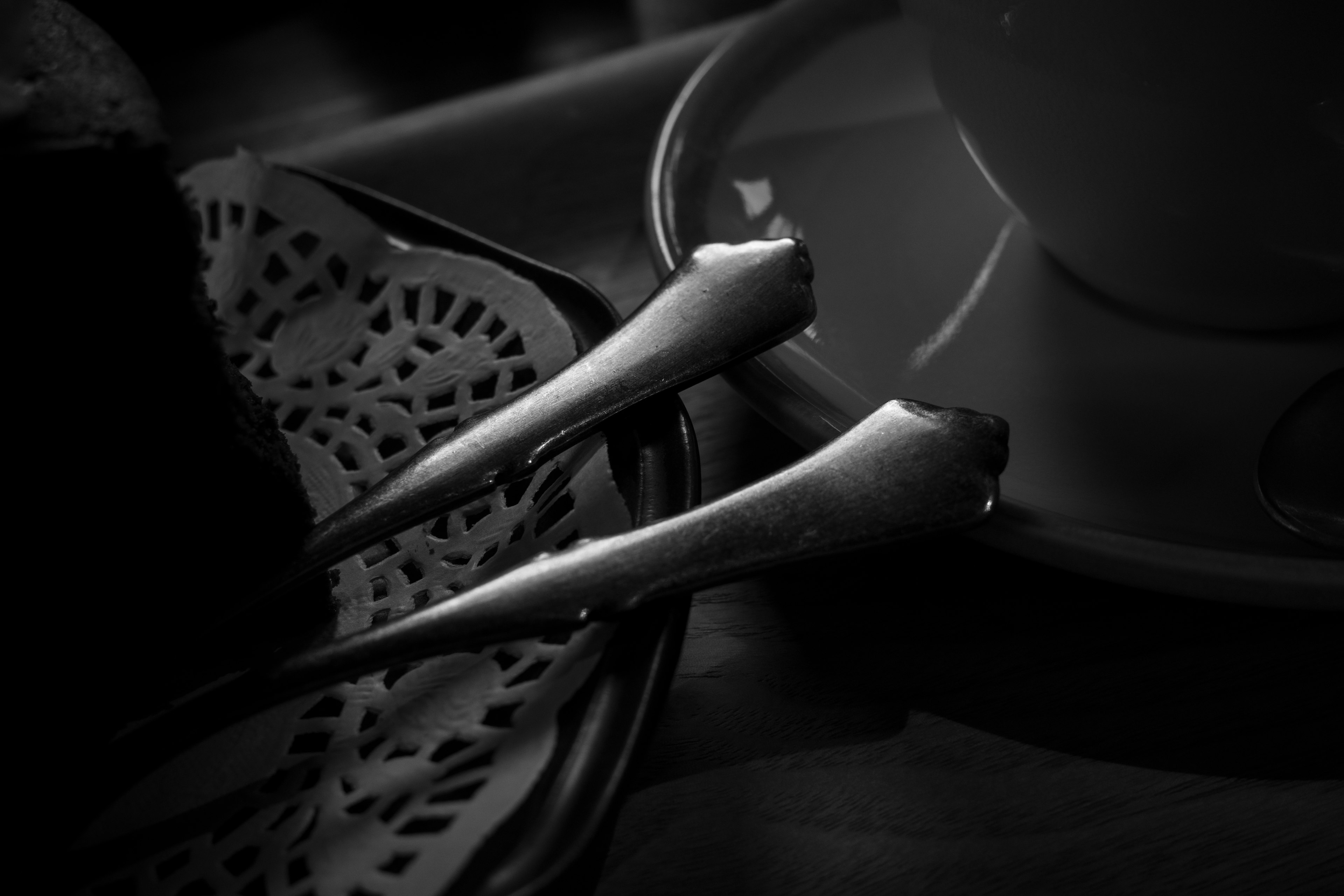 Una imagen en blanco y negro que muestra una taza de café y un tenedor plateado sobre una mesa