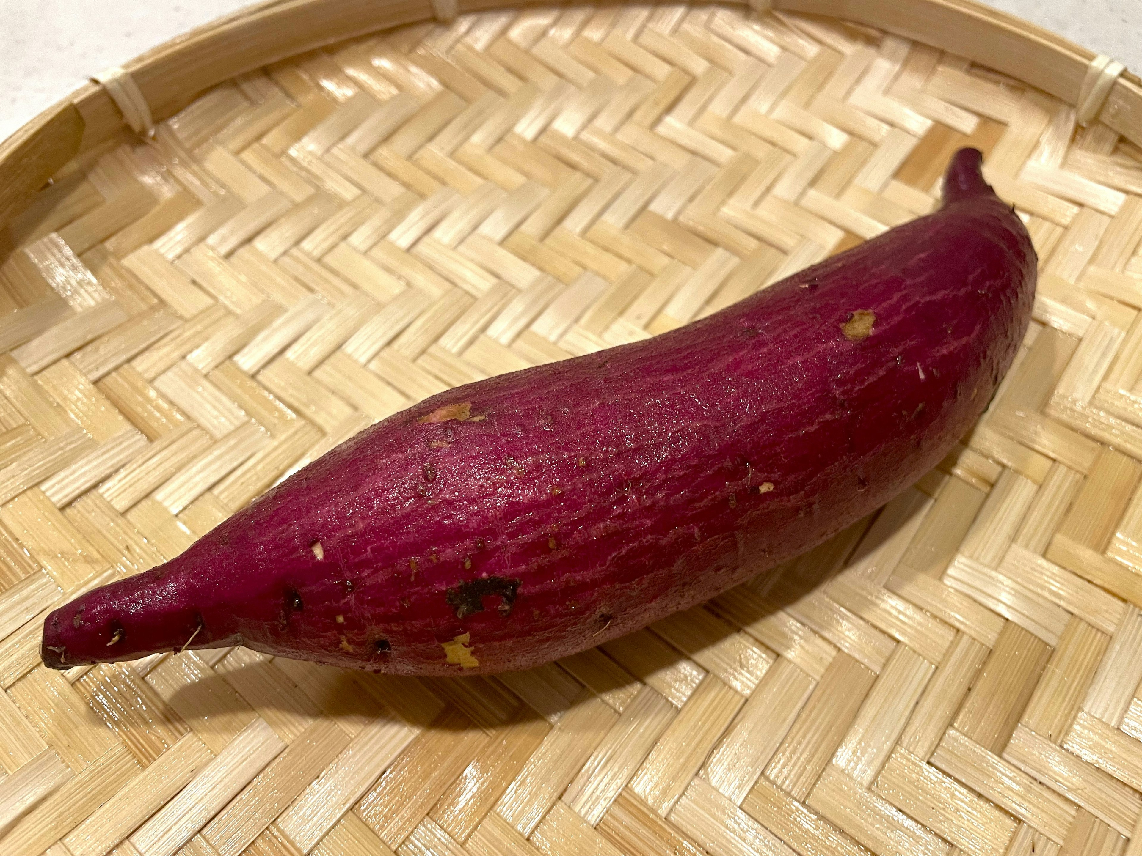 A purple sweet potato resting on a woven basket