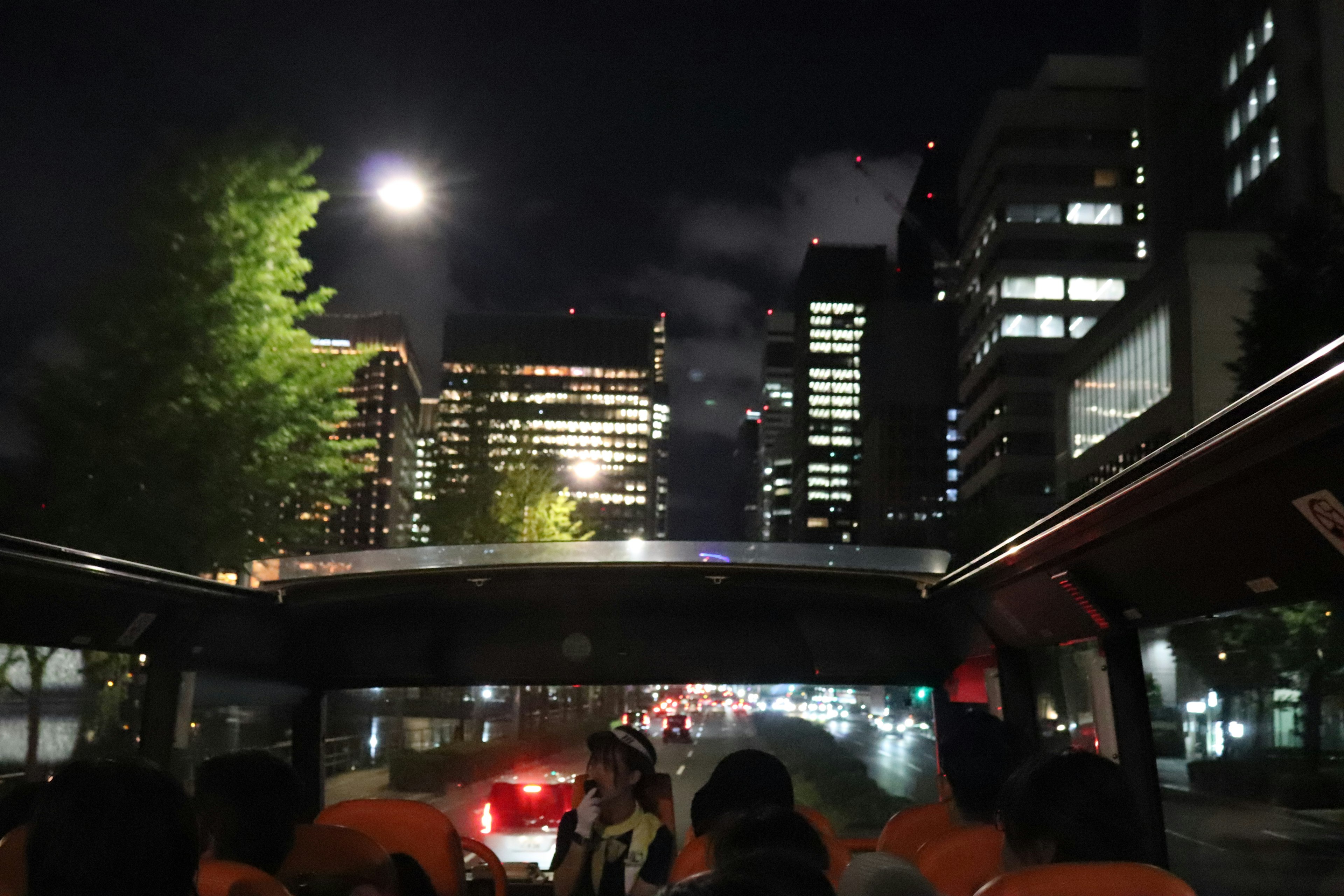 Passengers enjoying the night cityscape from an open-top bus