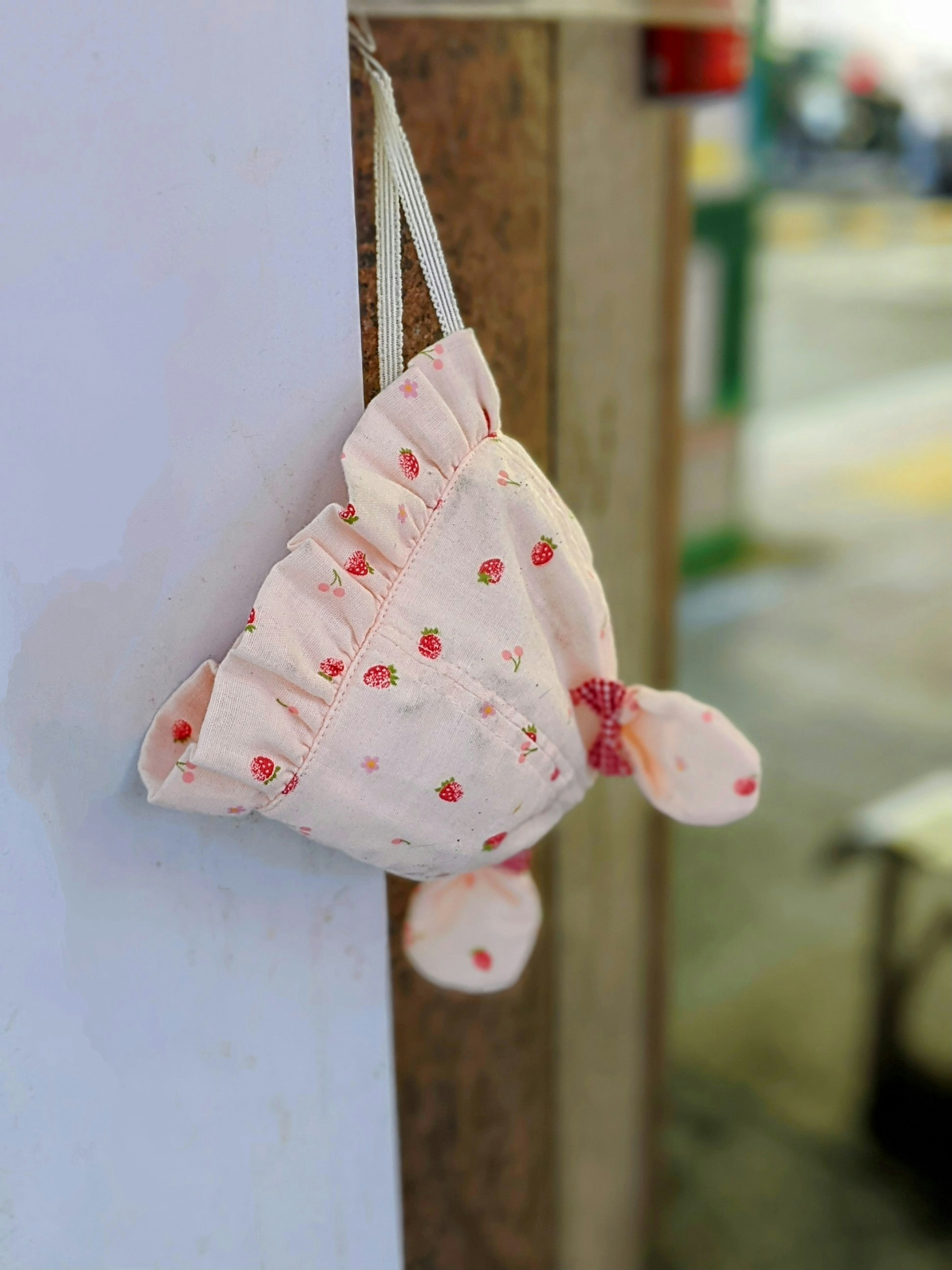 A pink polka dot fabric plush toy hanging on a wall