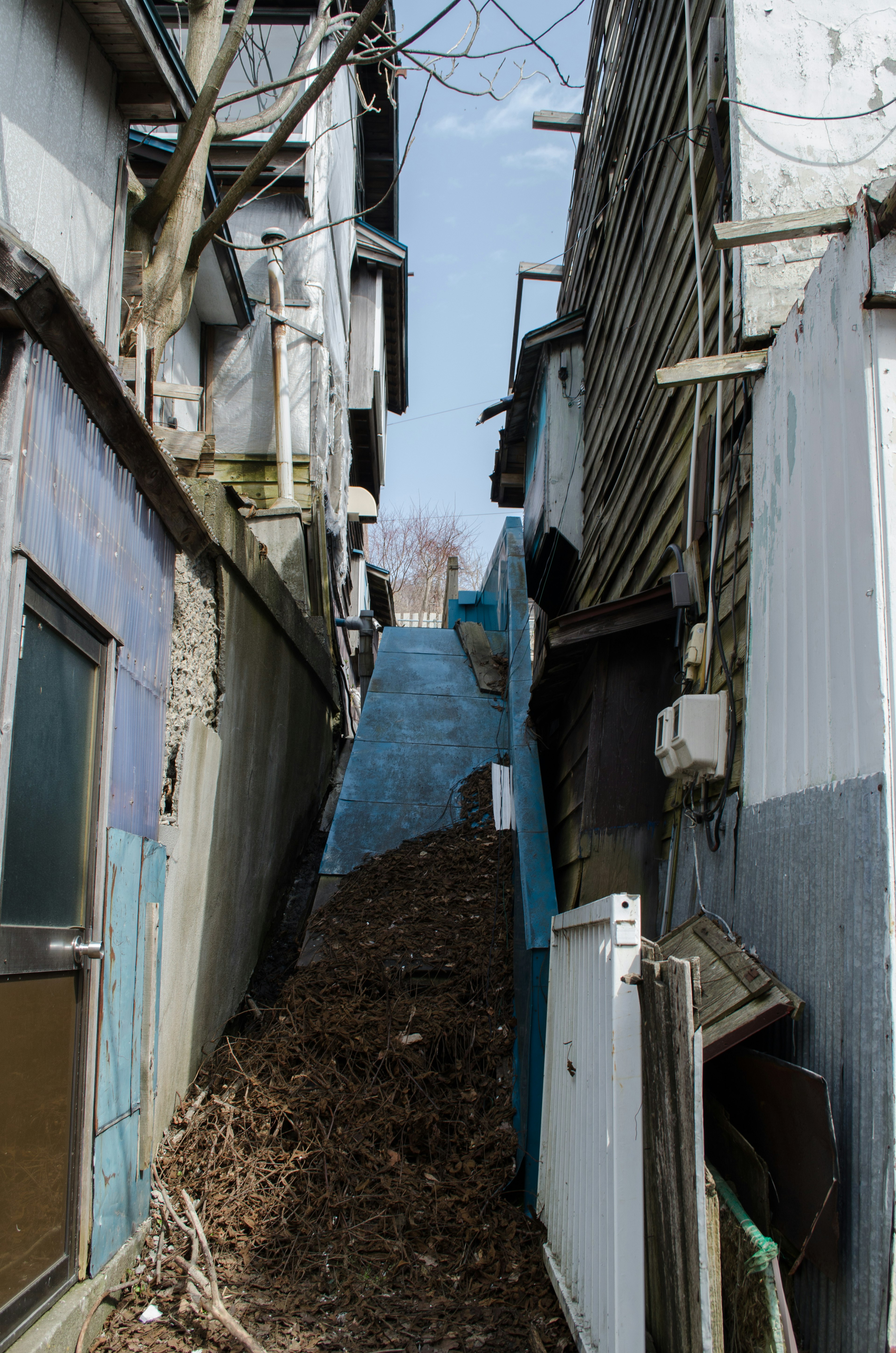 Schmale Gasse, gesäumt von alten Gebäuden und einer blauen Wand