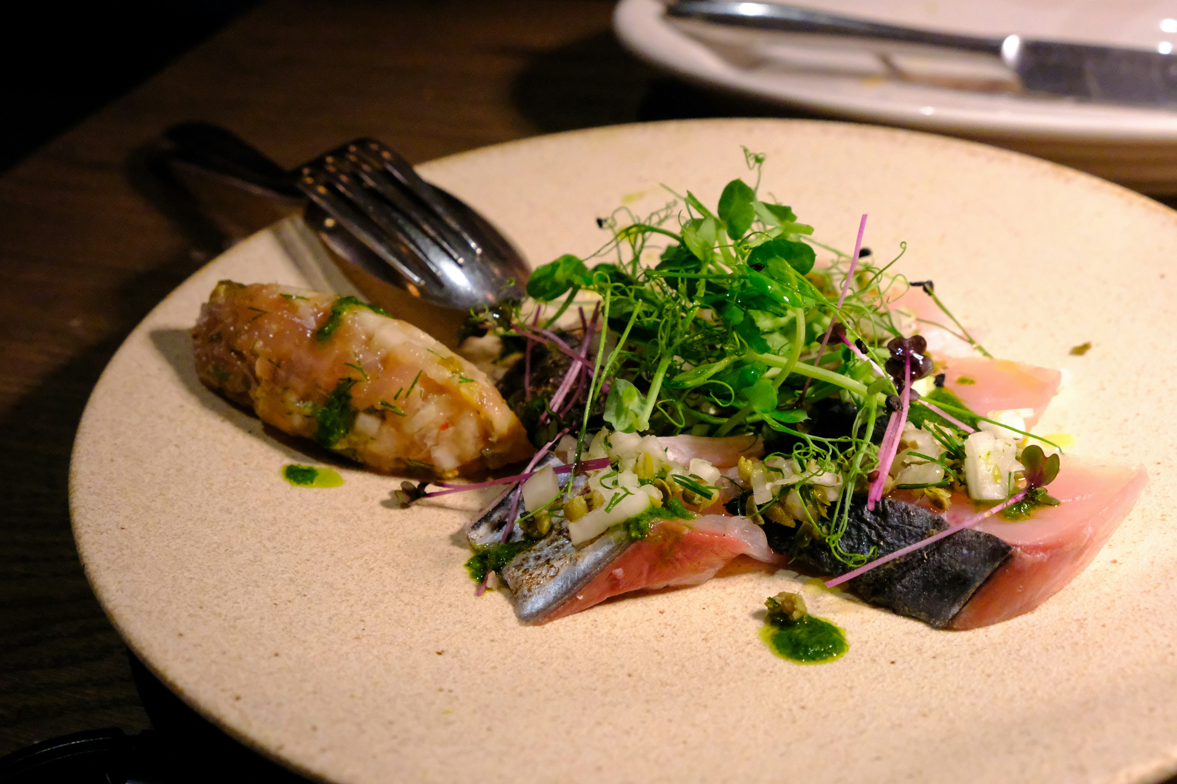 Plate featuring sliced cured ham and fresh herb salad