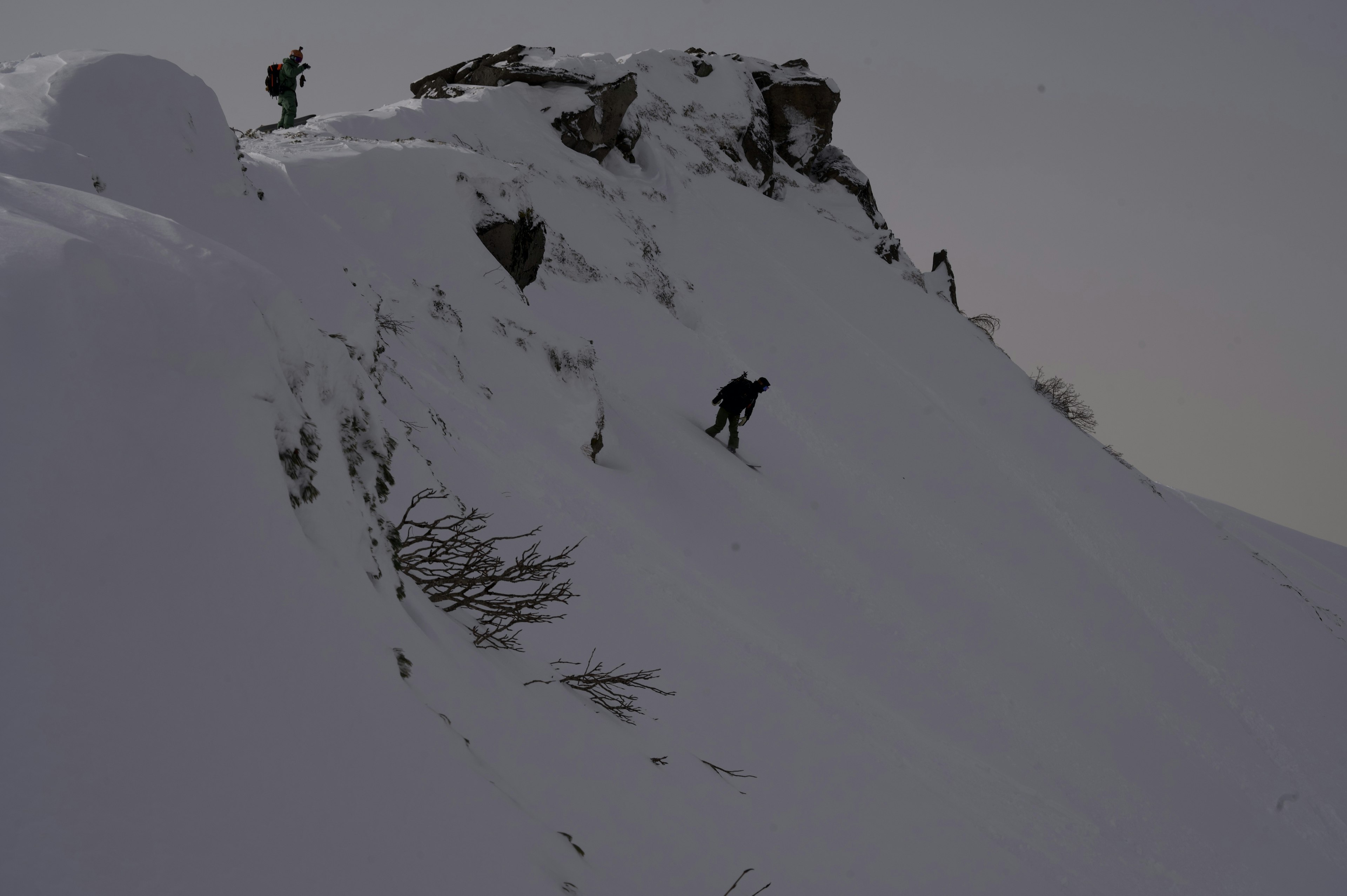 Escaladores navegando por una cresta montañosa nevada en un día nublado