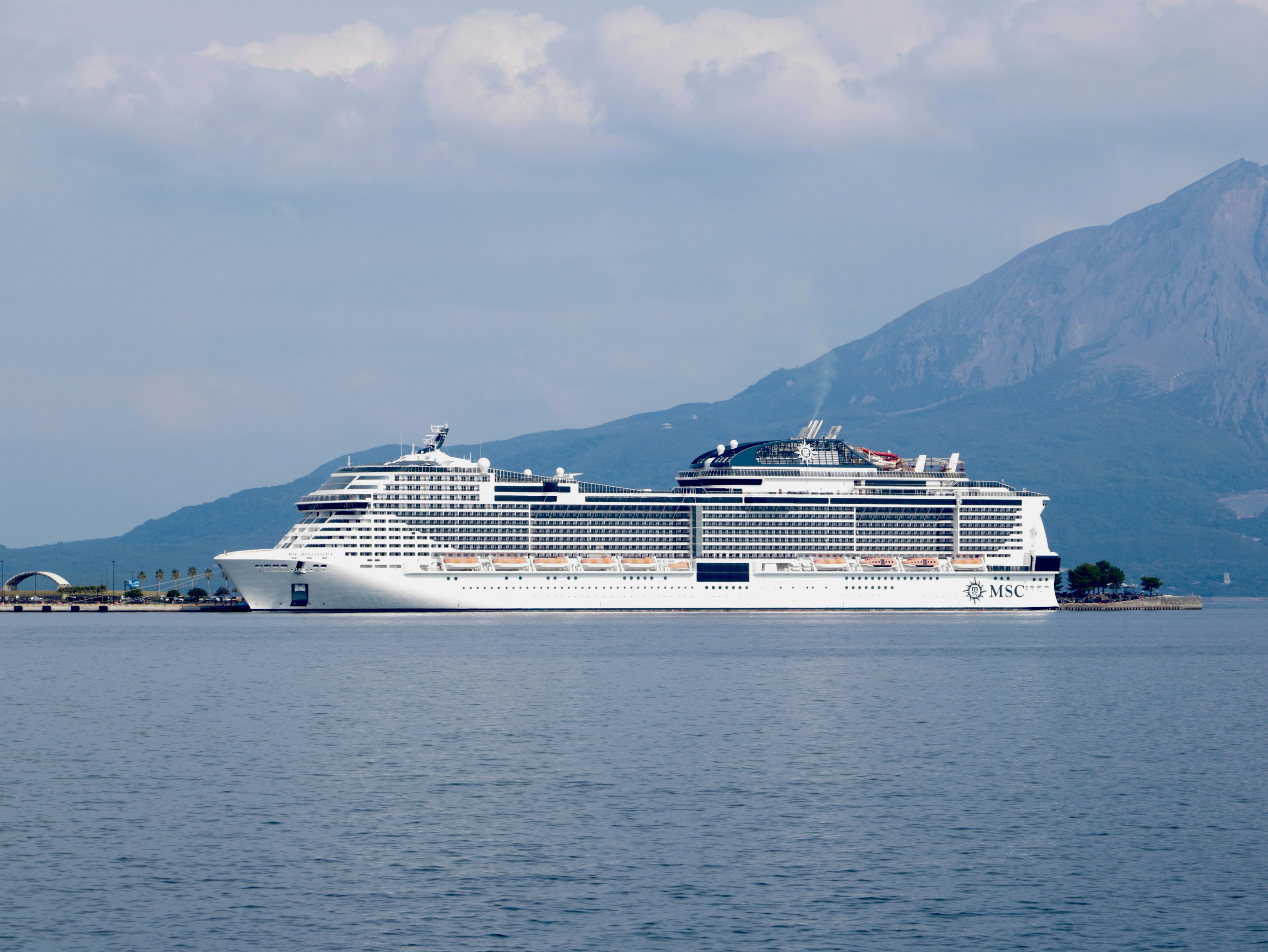 Un gran crucero navegando en aguas tranquilas con montañas al fondo