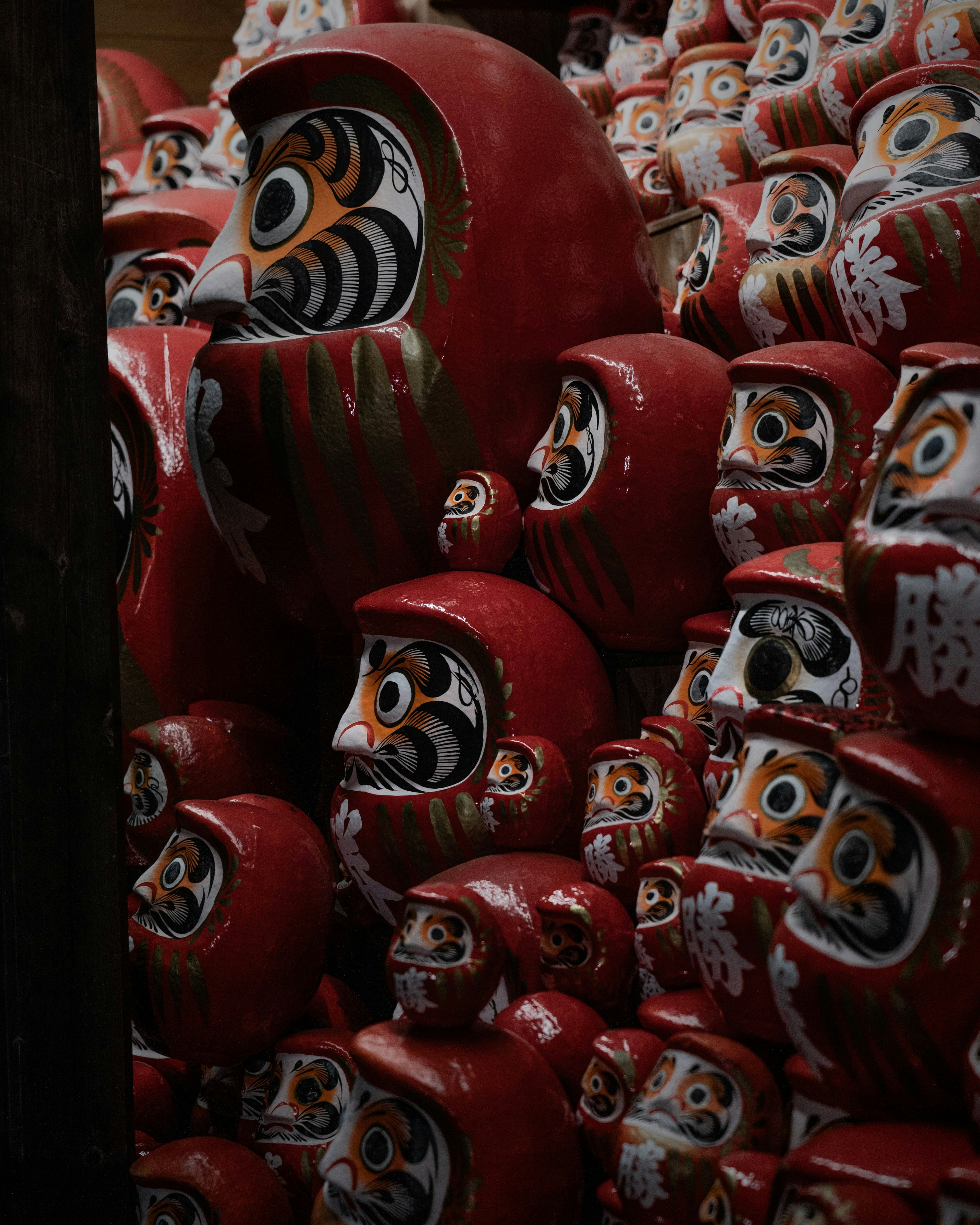 A collection of red Daruma dolls stacked closely together