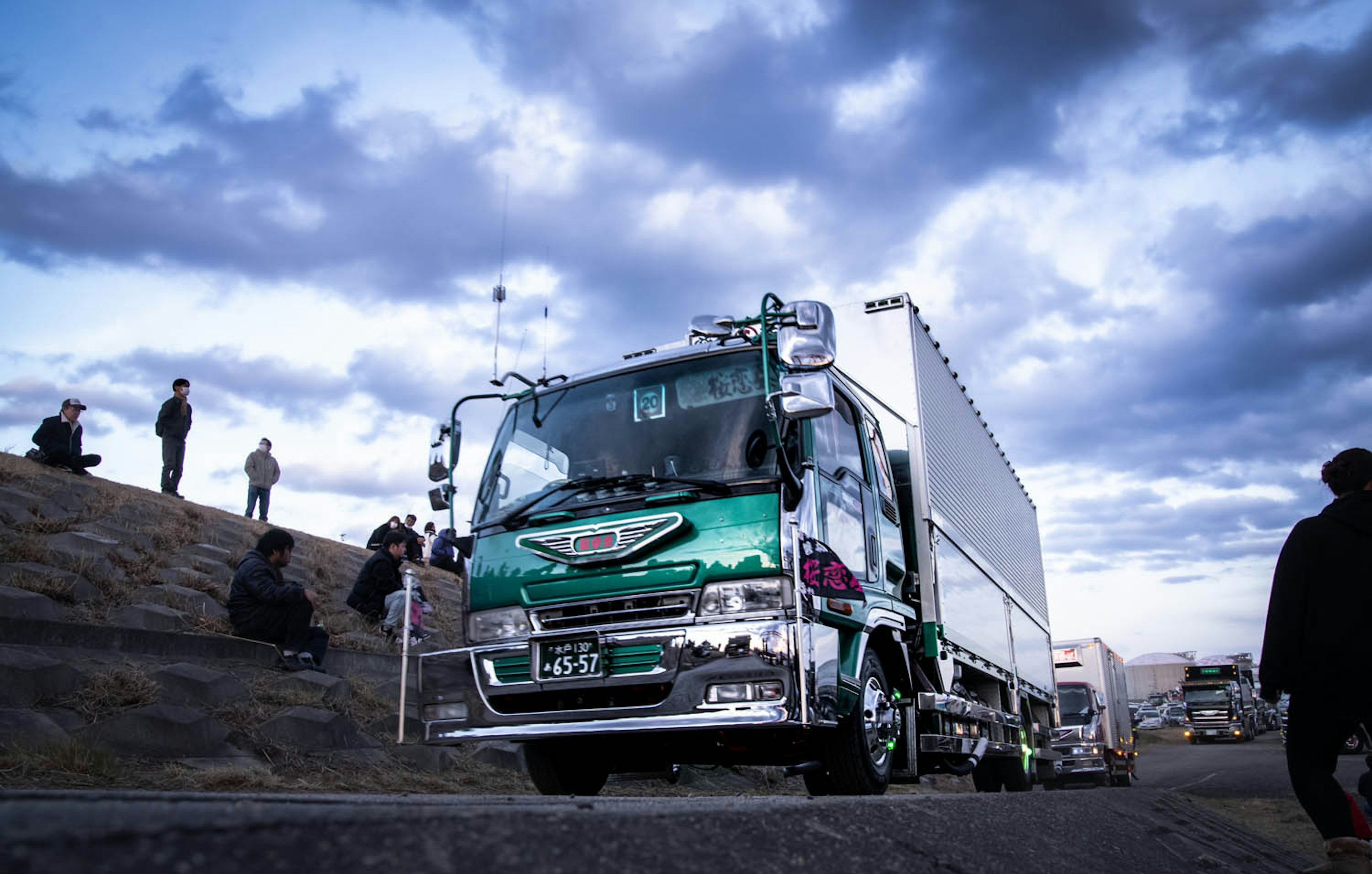 Camion circulant sous un ciel bleu avec des nuages et des spectateurs