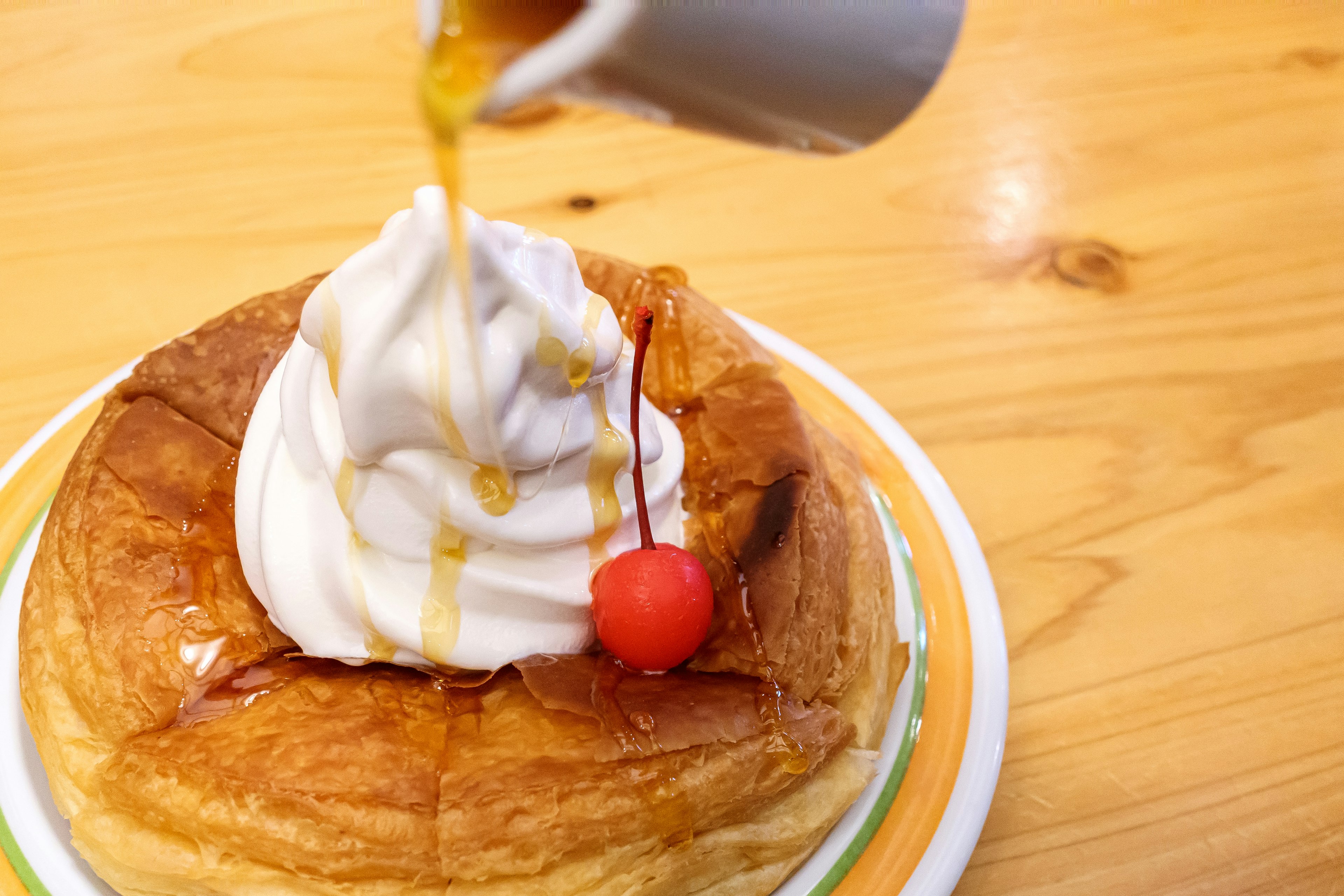 Panqueque cubierto con crema batida y cereza rociado con jarabe