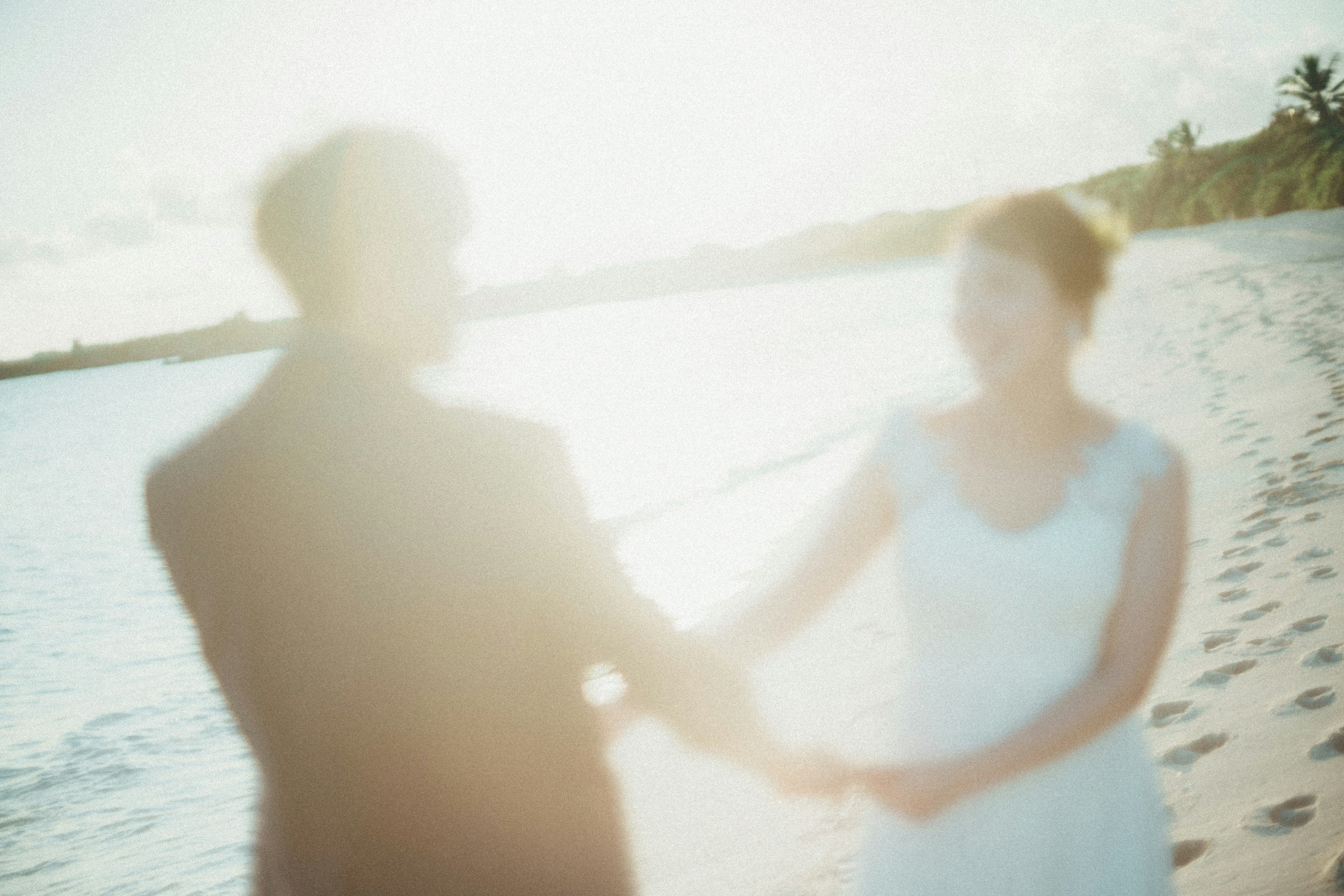 Blurred image of a couple holding hands by the beach