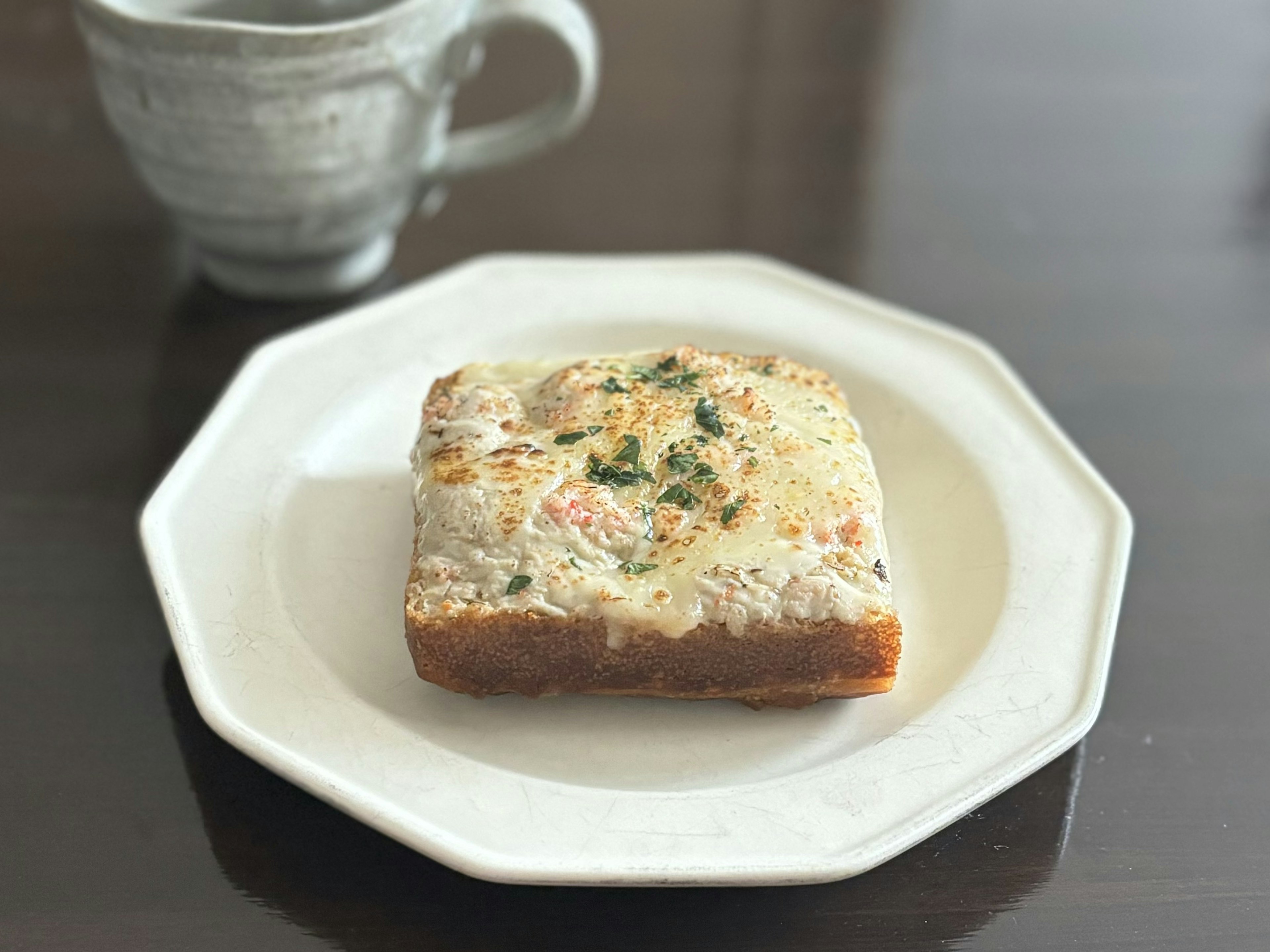 흰 접시 위에 놓인 구운 빵과 배경의 커피 컵