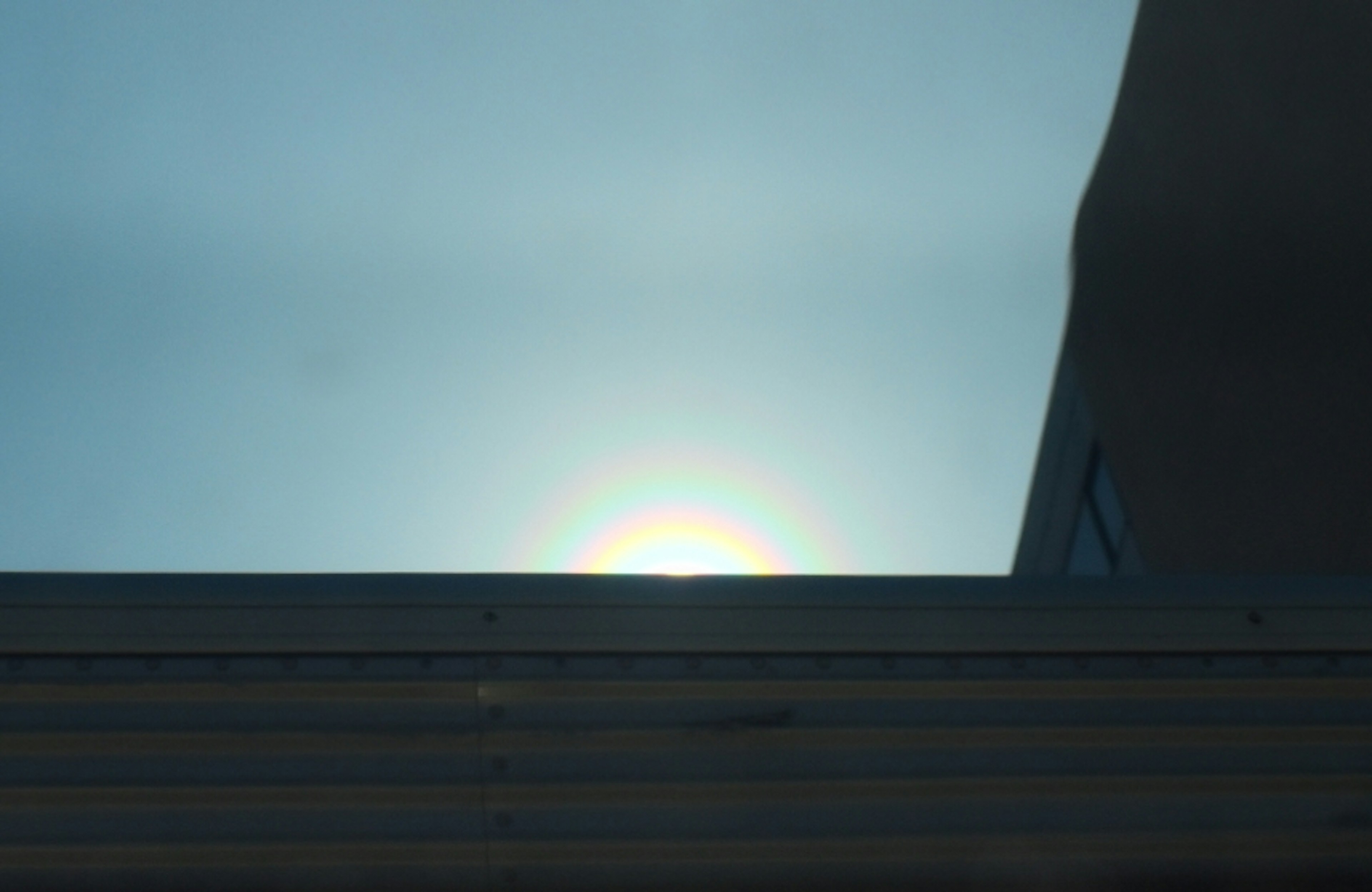 Lever de soleil avec la silhouette d'un bâtiment contre un ciel bleu