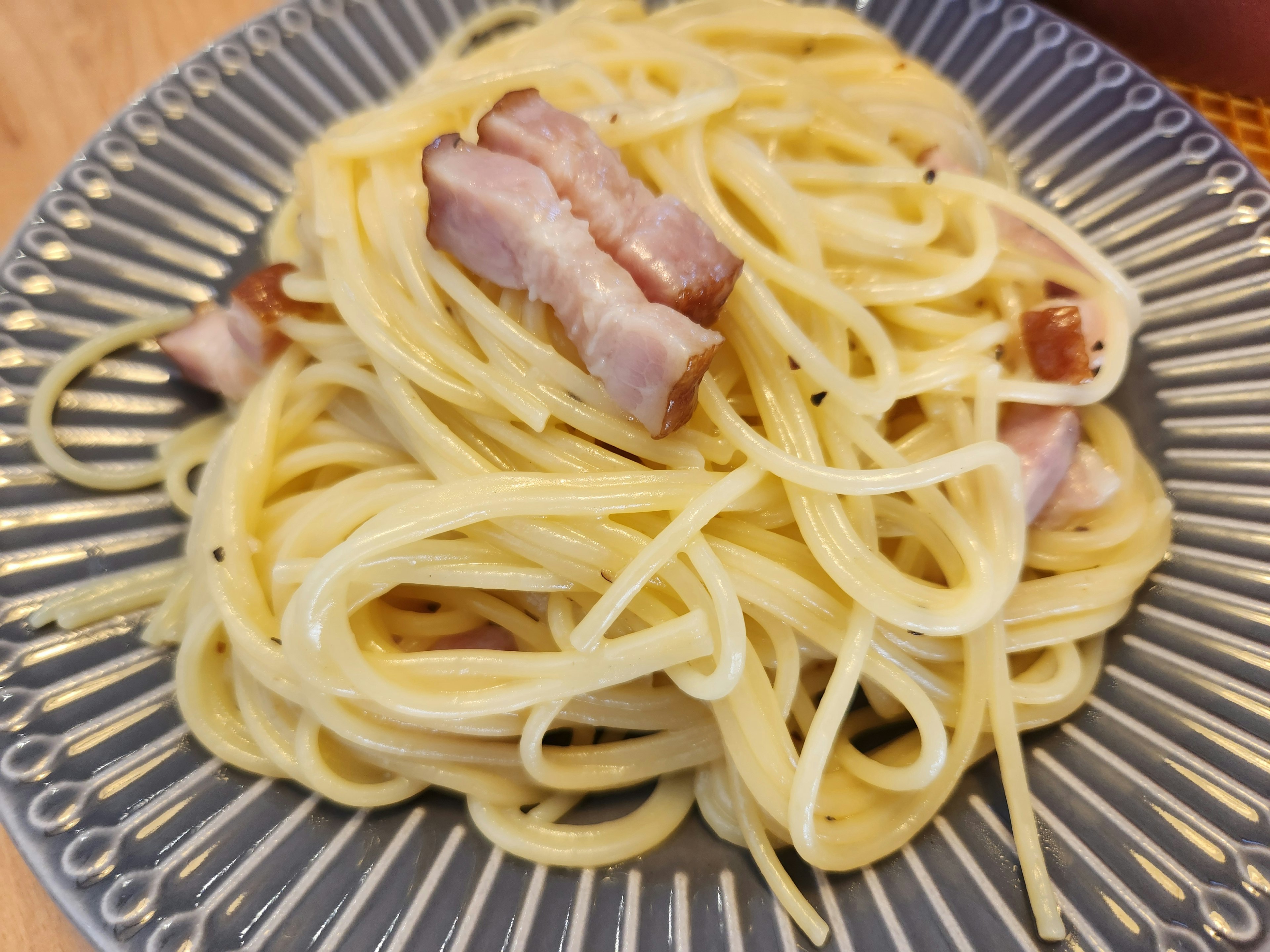 クリームソースのスパゲッティに豚肉のスライスがトッピングされた料理