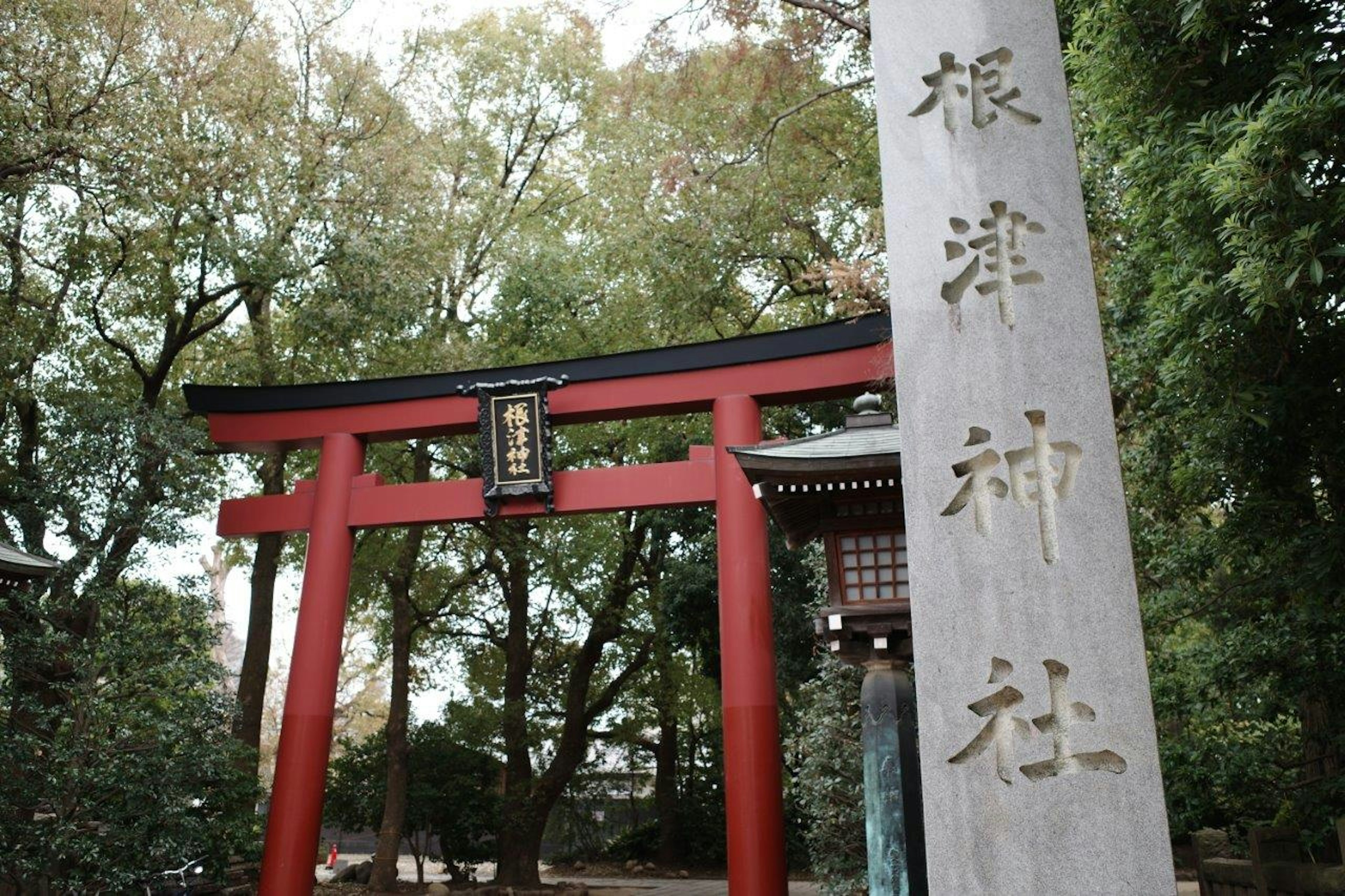 赤い鳥居の前に立つ神社の石碑の写真