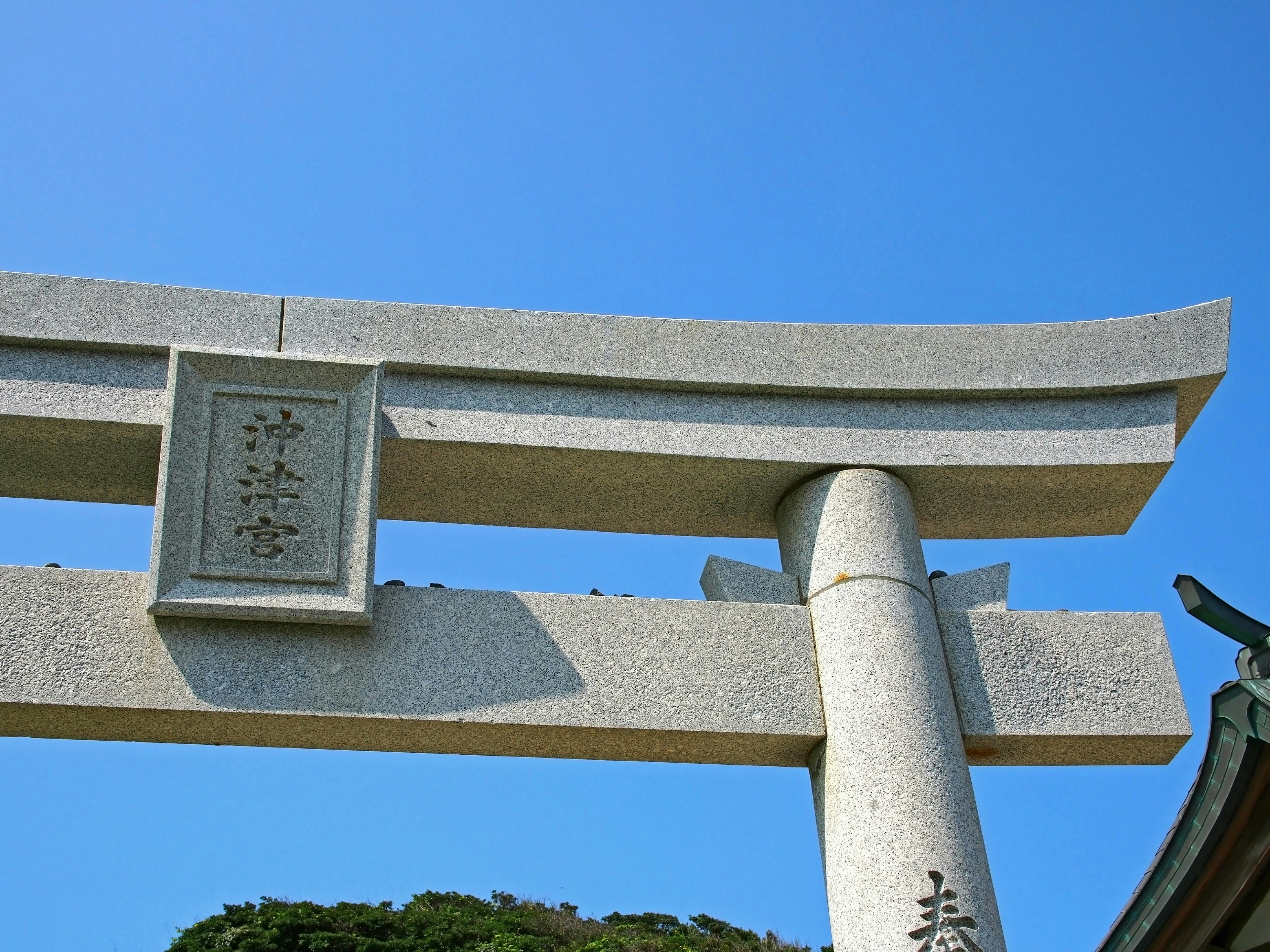 Stone torii gate under a blue sky with an inscription plaque