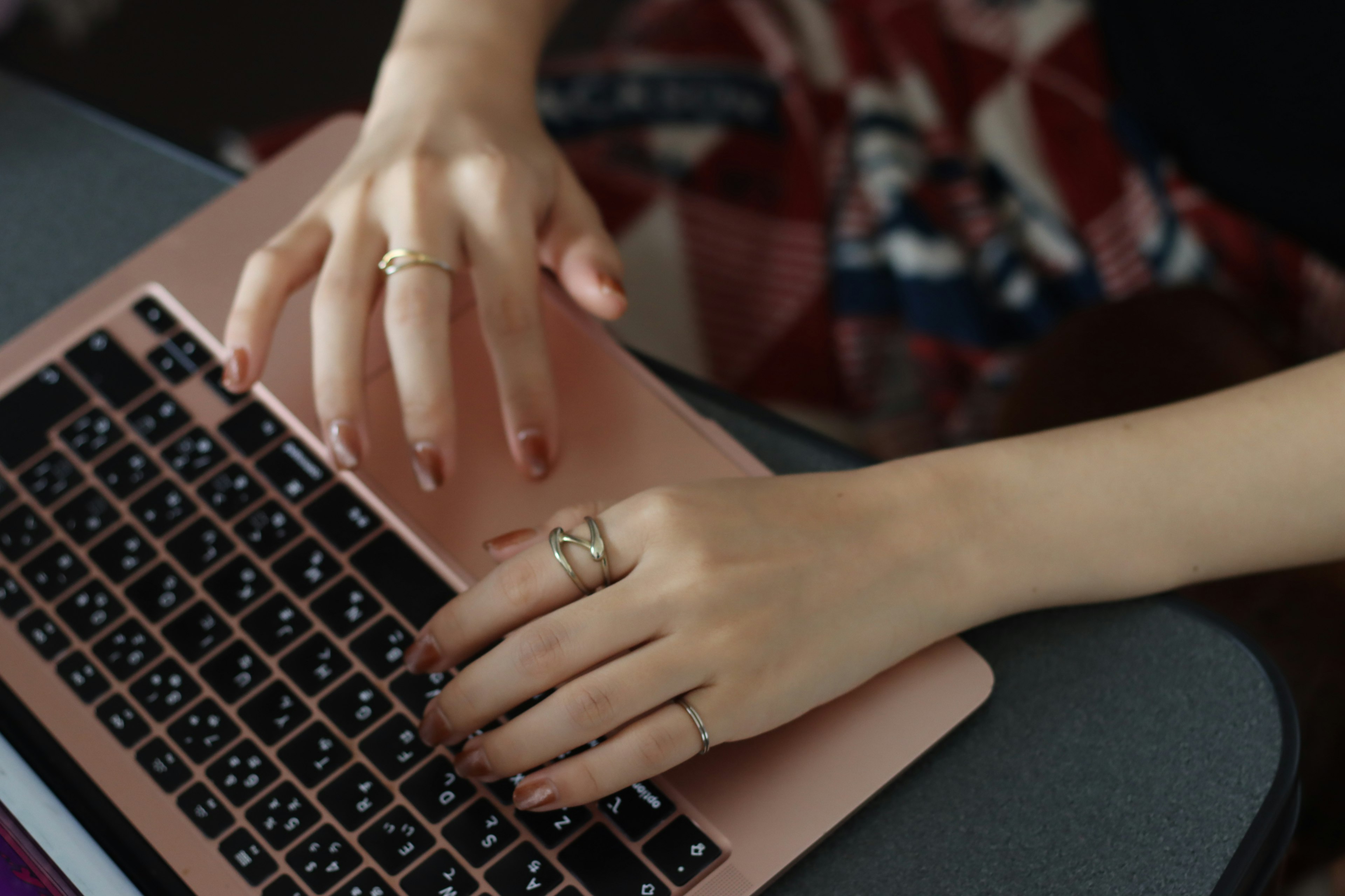 Image of hands typing on a laptop Multiple rings on fingers Hands appear elegant and refined