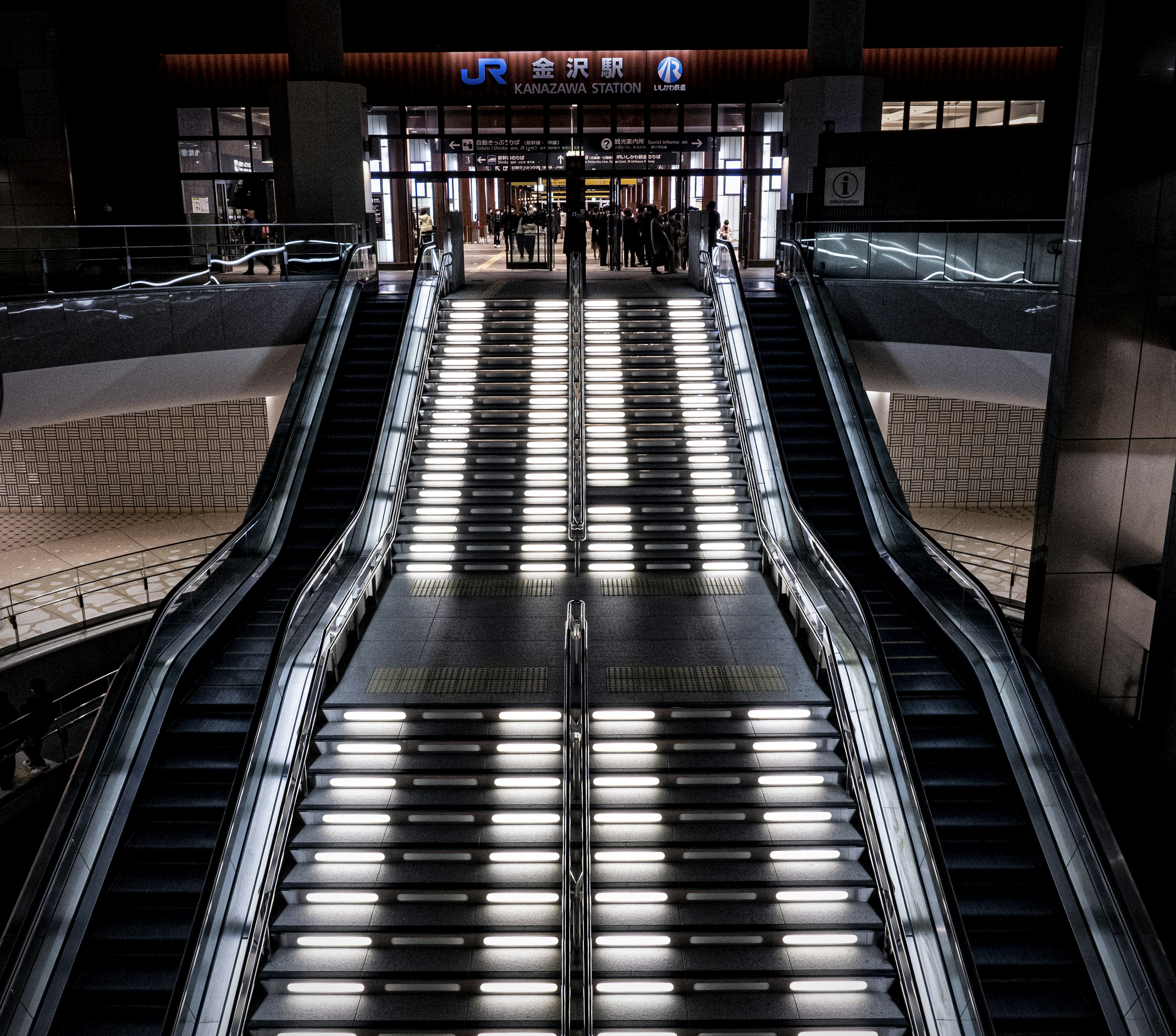 Scale mobile moderna con illuminazione brillante al centro di un interno di stazione