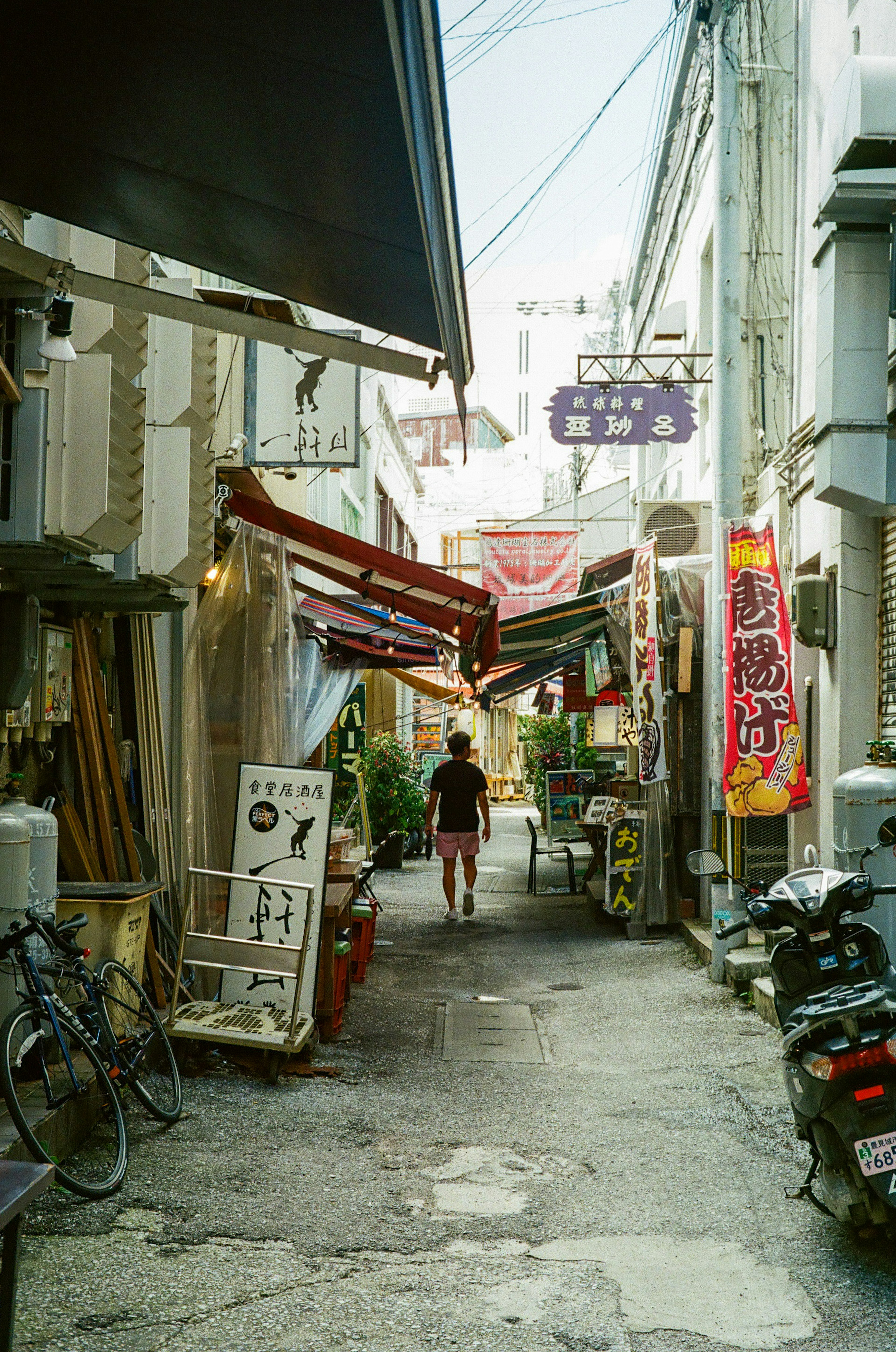 Ruelle étroite avec une personne marchant des vélos et des enseignes de magasin visibles