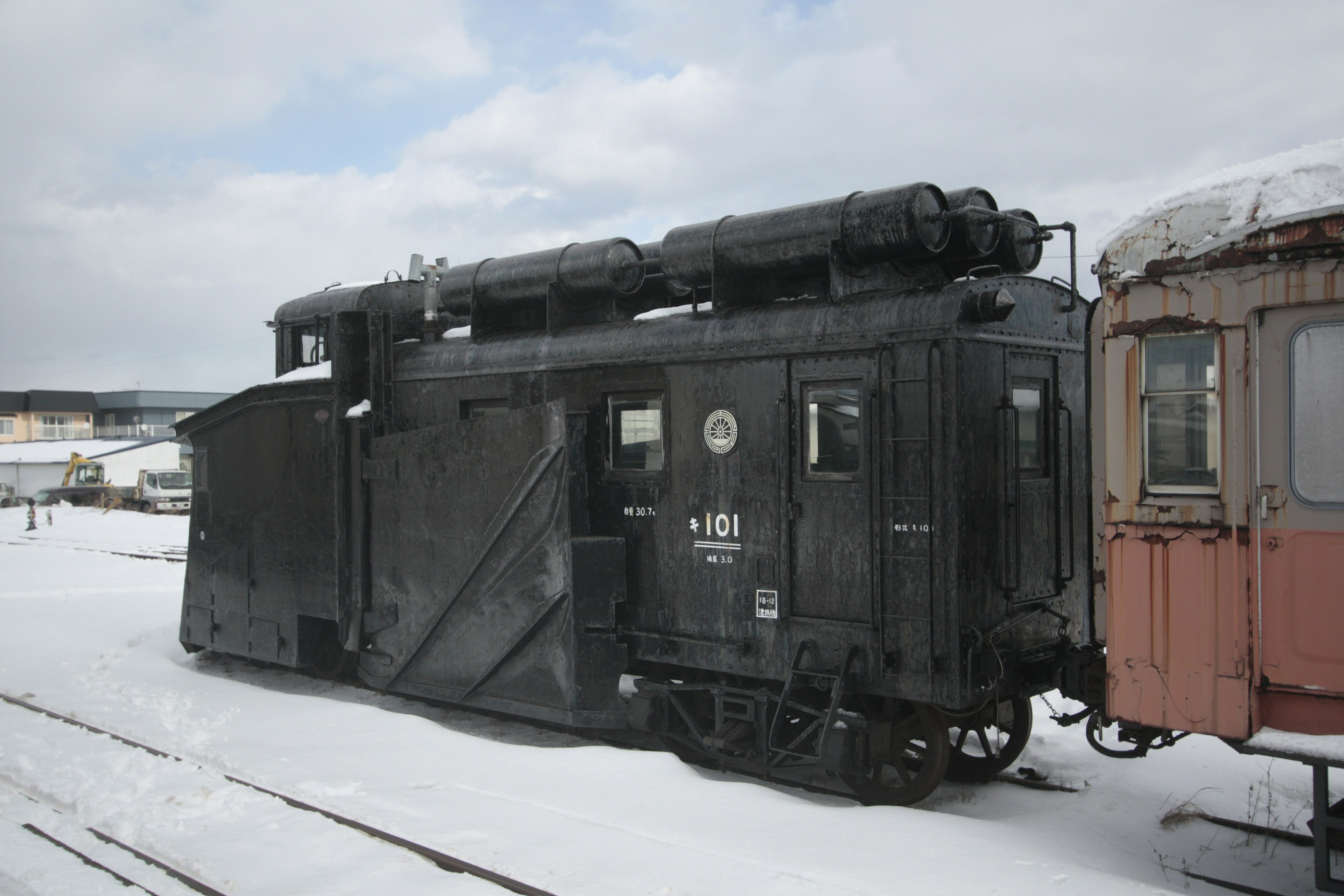 Alte schwarze Lokomotive neben einem Waggon auf Schnee