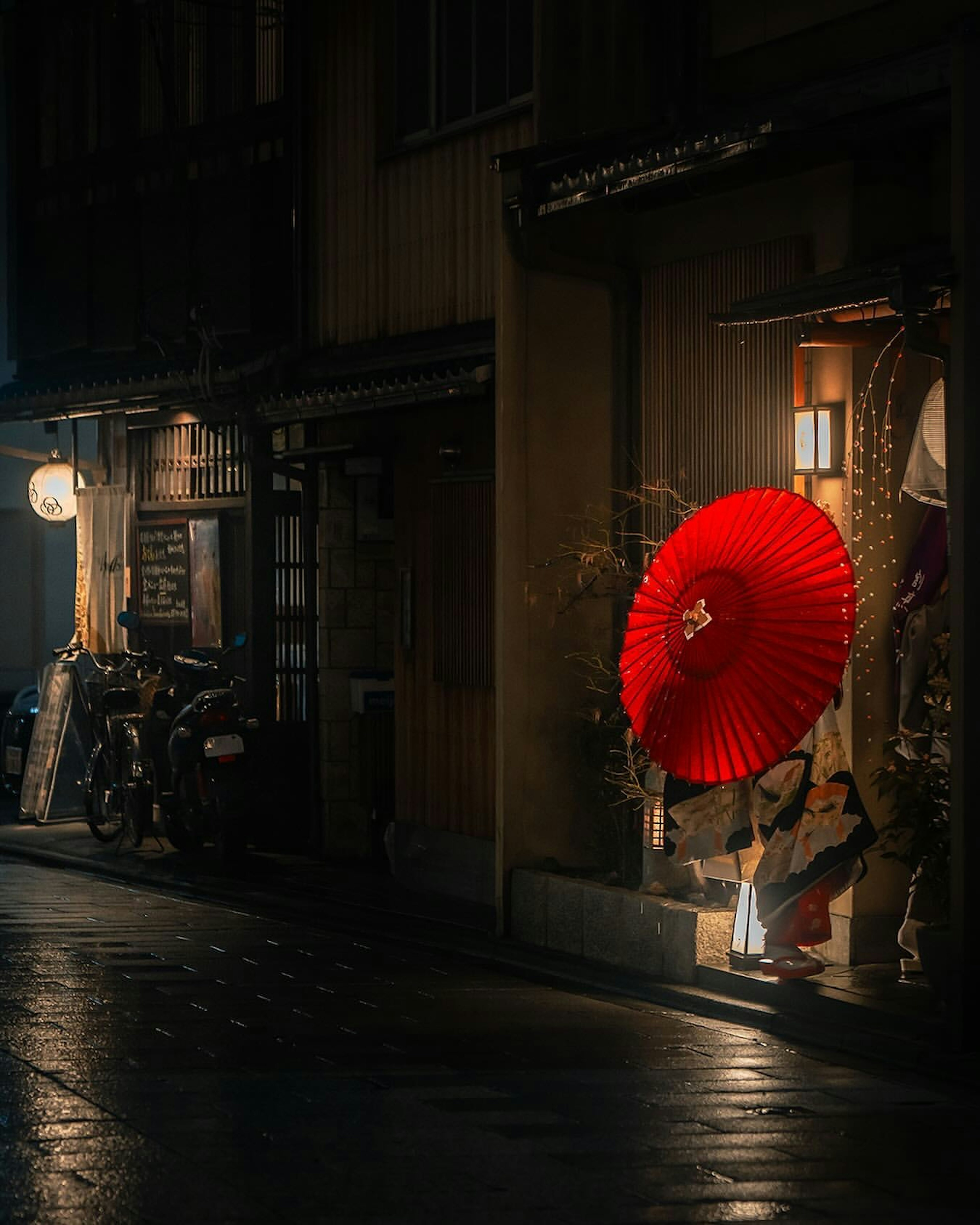 赤い傘を持った女性が薄暗い路地に立っている情景