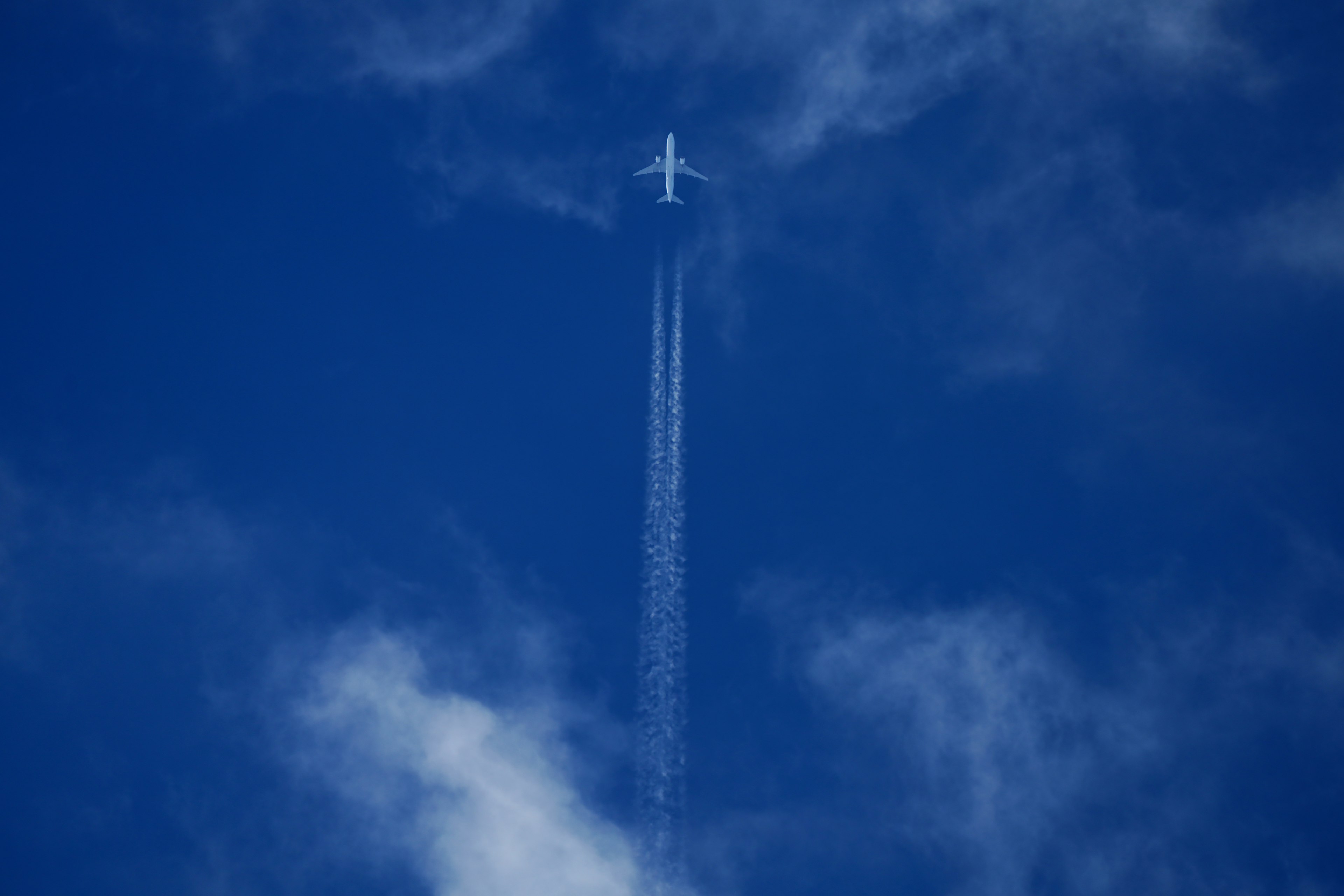 Un aereo che vola in un cielo blu chiaro con una scia bianca dietro di esso