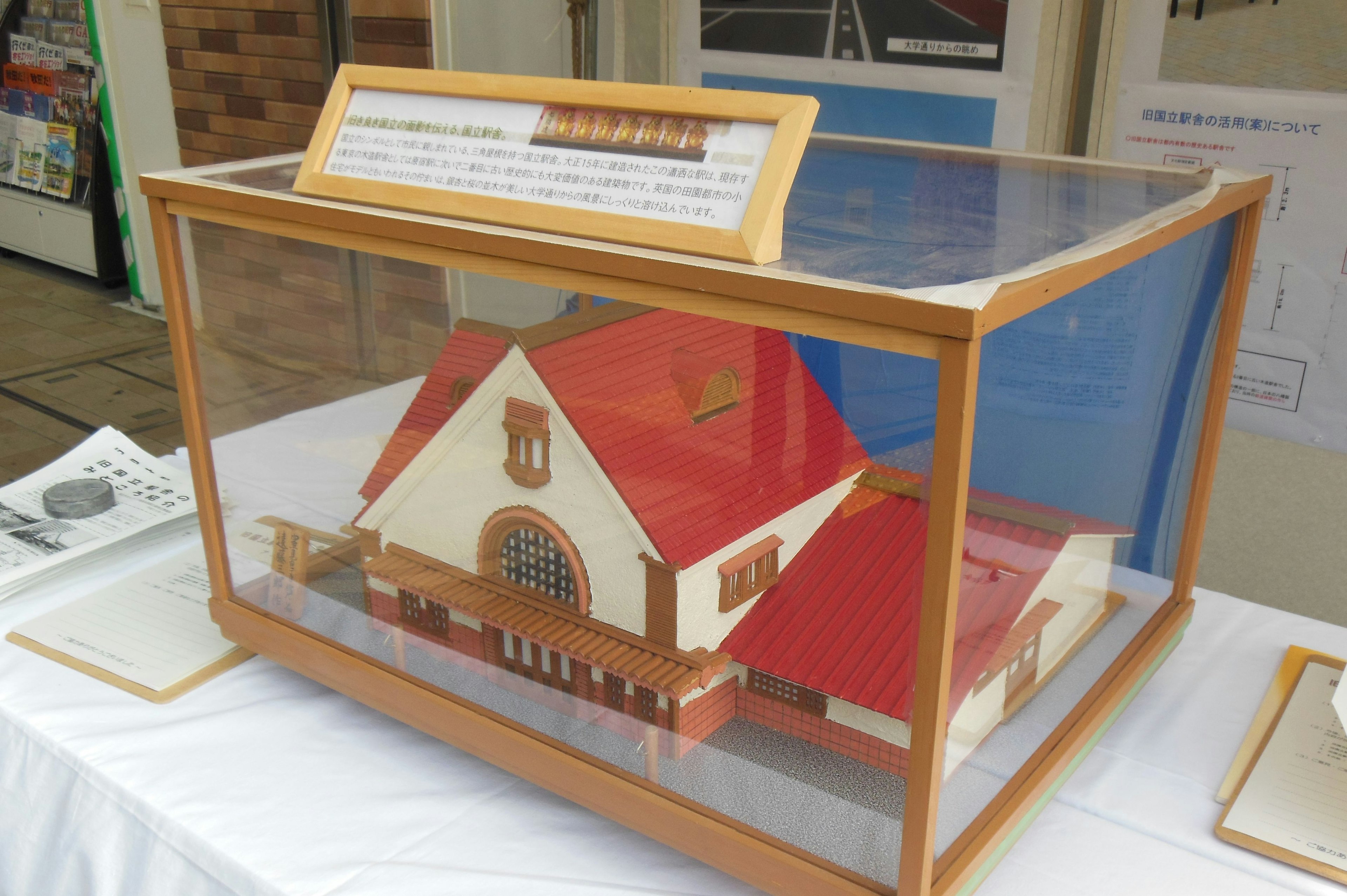 Maison modèle avec un toit rouge exposée dans une vitrine transparente