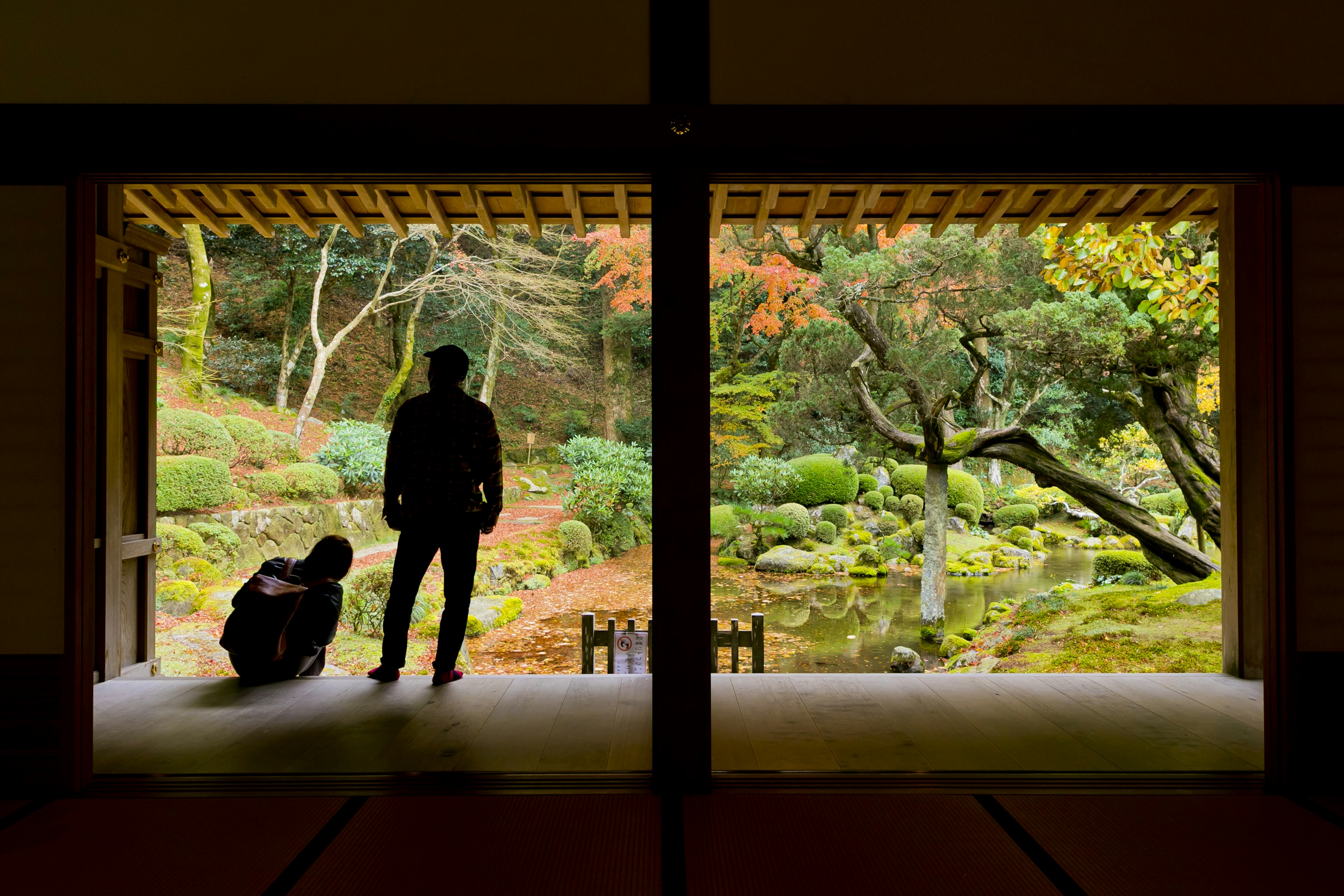 Deux personnes dans une pièce traditionnelle surplombant un jardin japonais