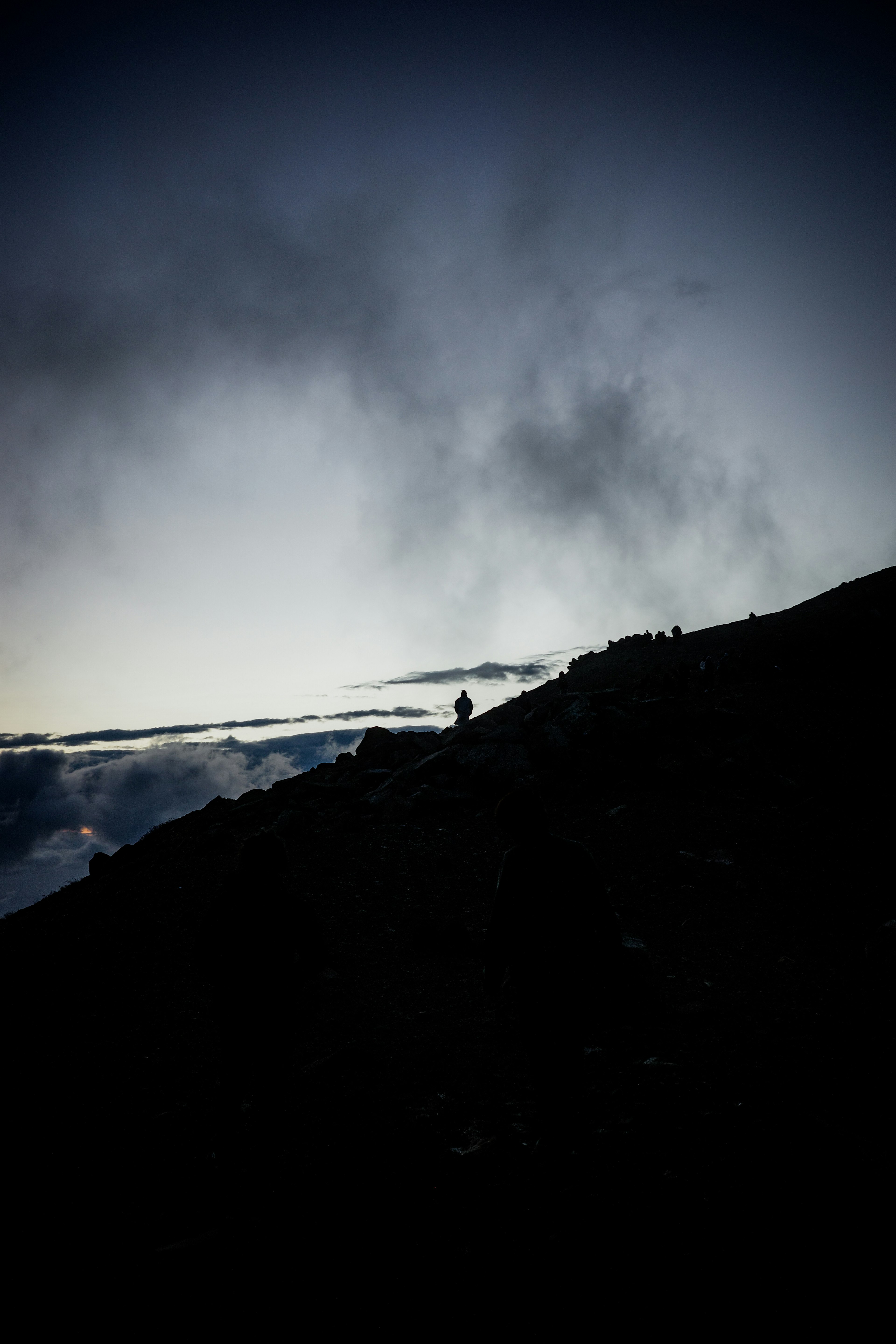 在黑暗山峰上站立的登山者轮廓