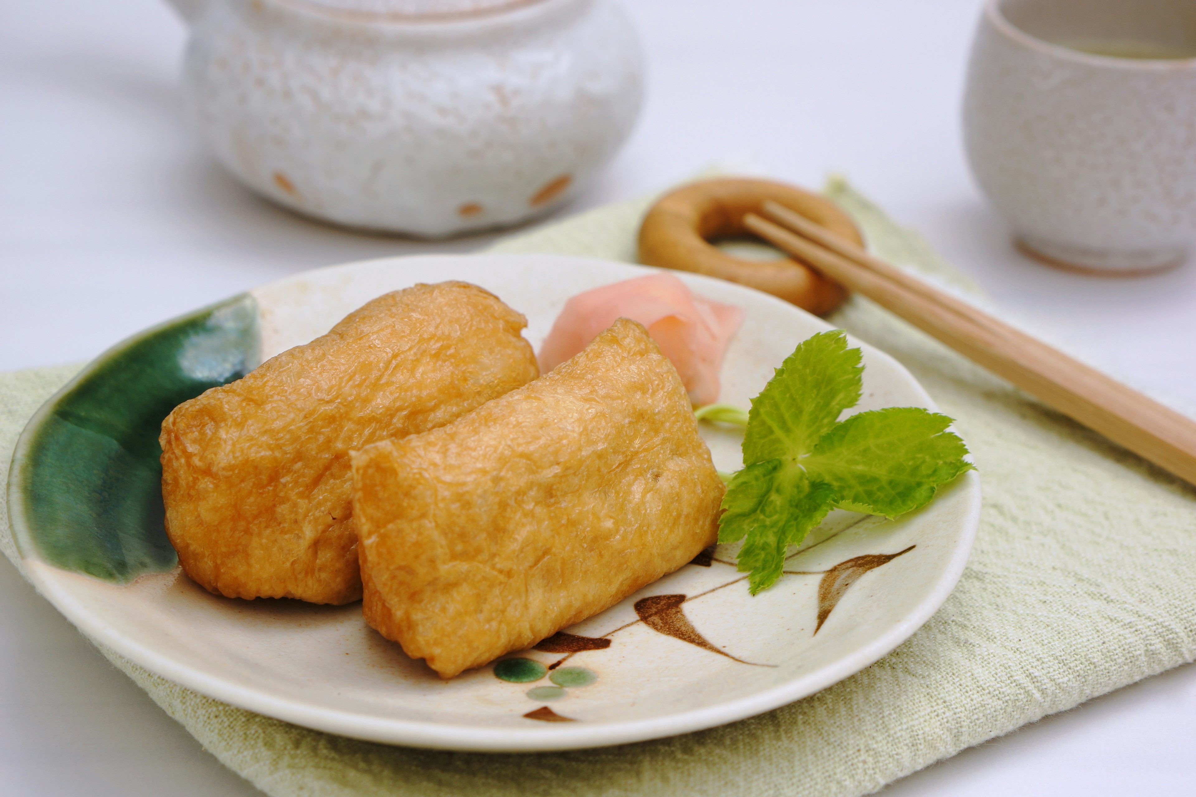 Frittierter Tofu auf einem Teller mit Minzblättern und eingelegtem Ingwer serviert