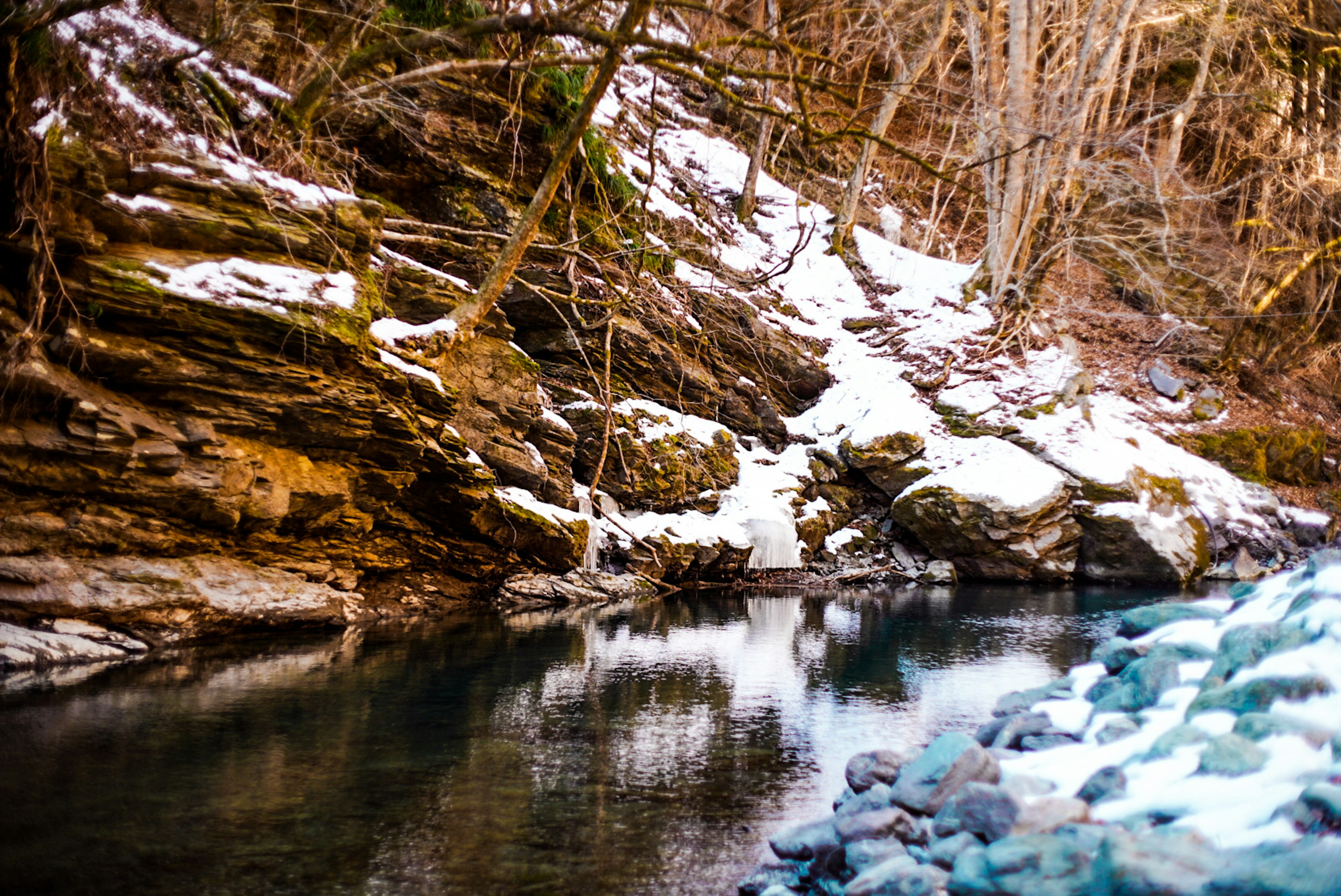 Paysage de rivière avec des rochers couverts de neige et une surface d'eau calme