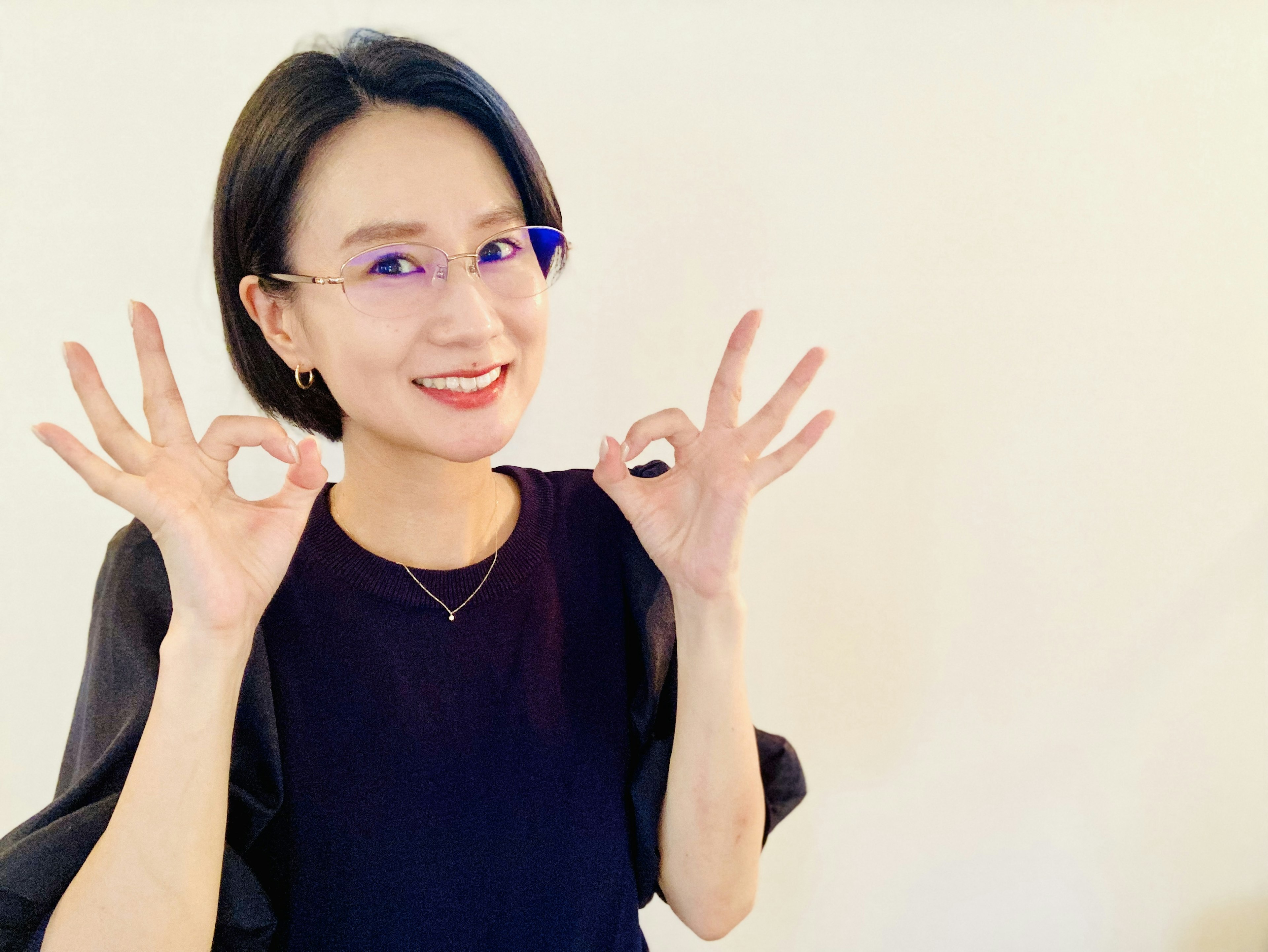 Woman in black top smiling and making OK sign with both hands