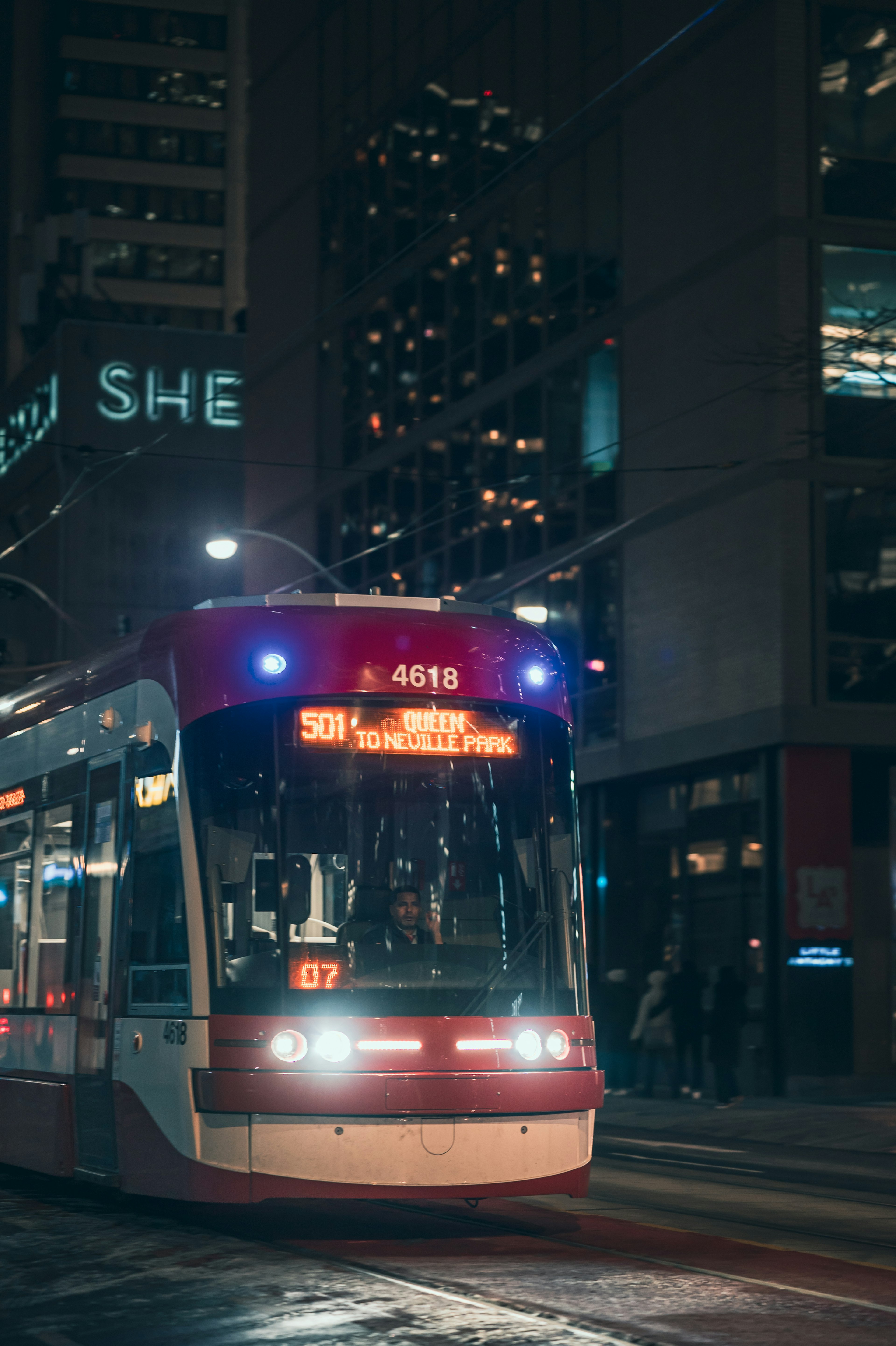 Roter Straßenbahn in der Stadt bei Nacht mit beleuchteten Gebäuden