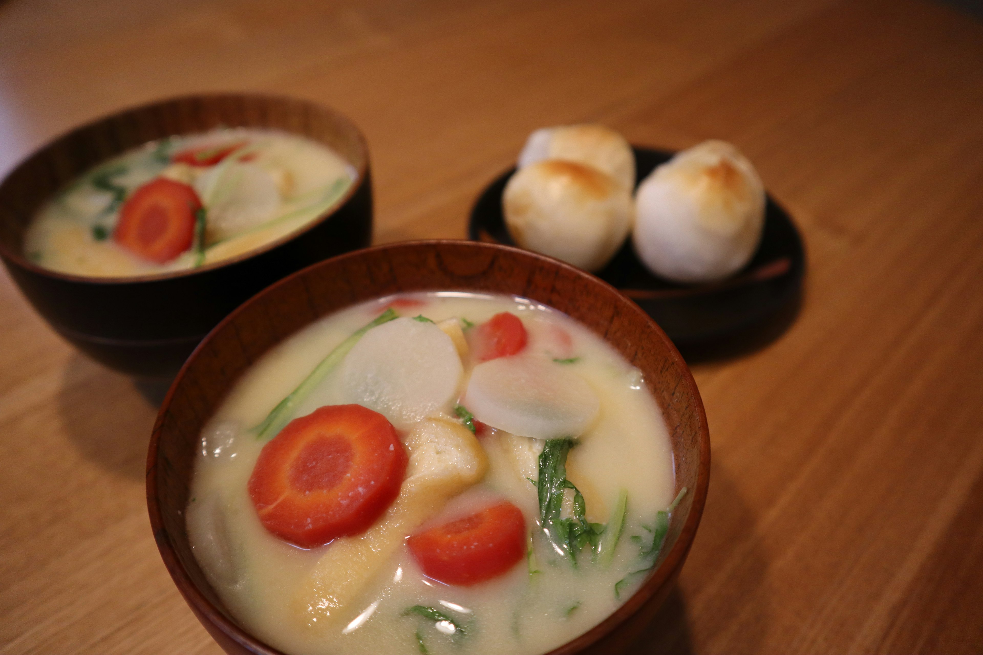 Leckere Suppe mit Gemüse und runden weißen Brötchen