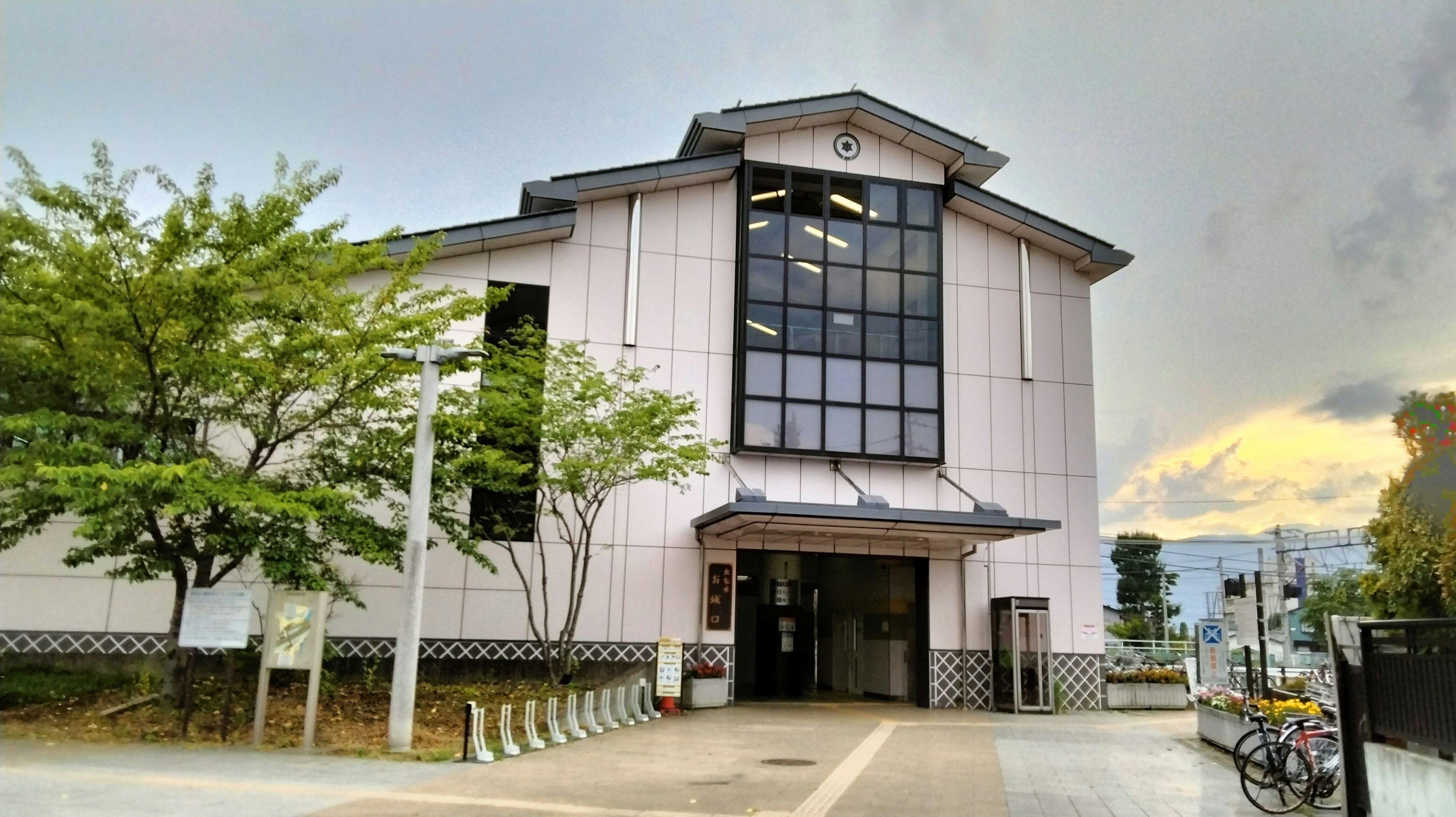 Exterior view of a light pink building with large windows surrounded by green trees