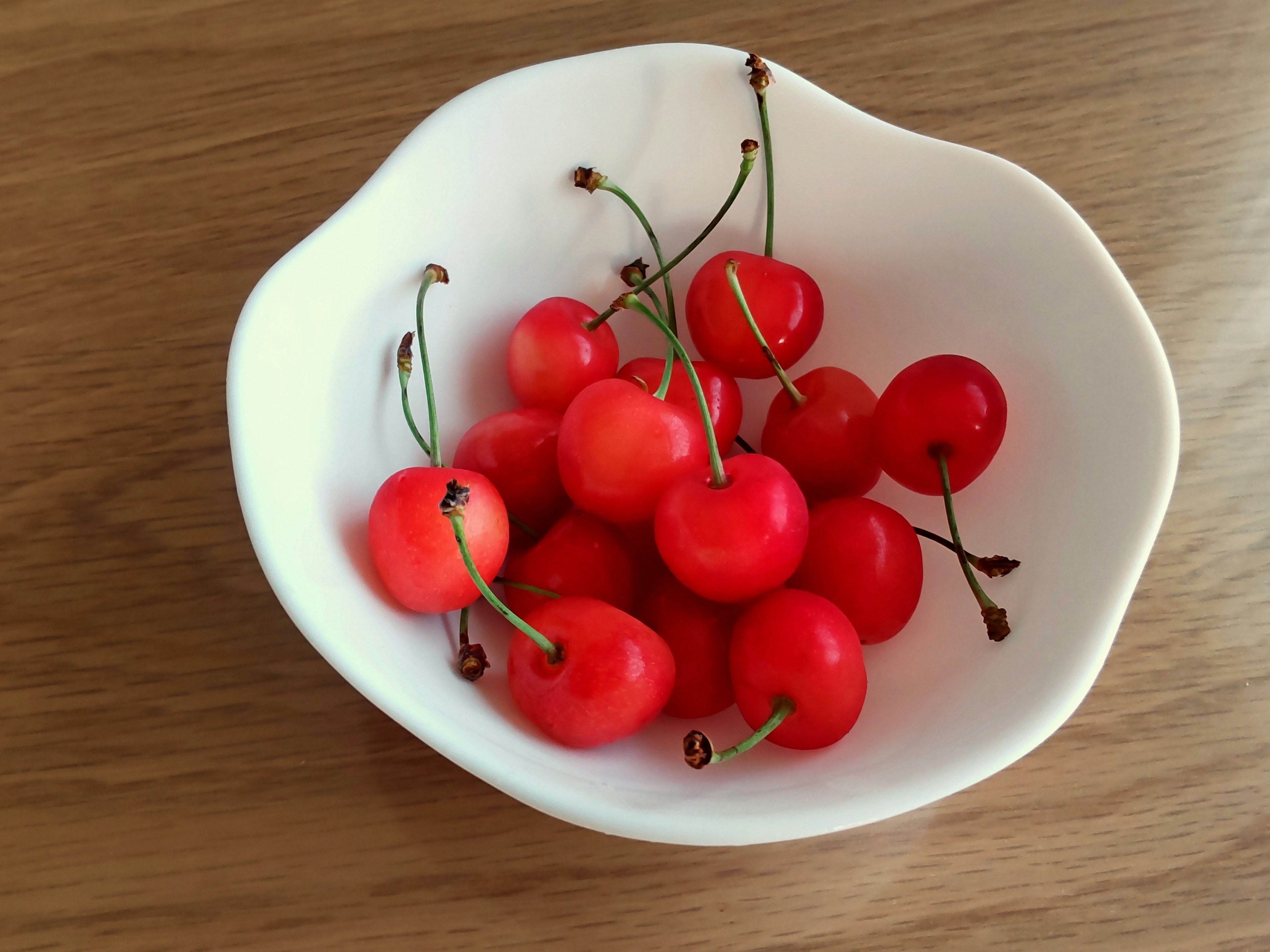 Red cherries arranged in a white bowl