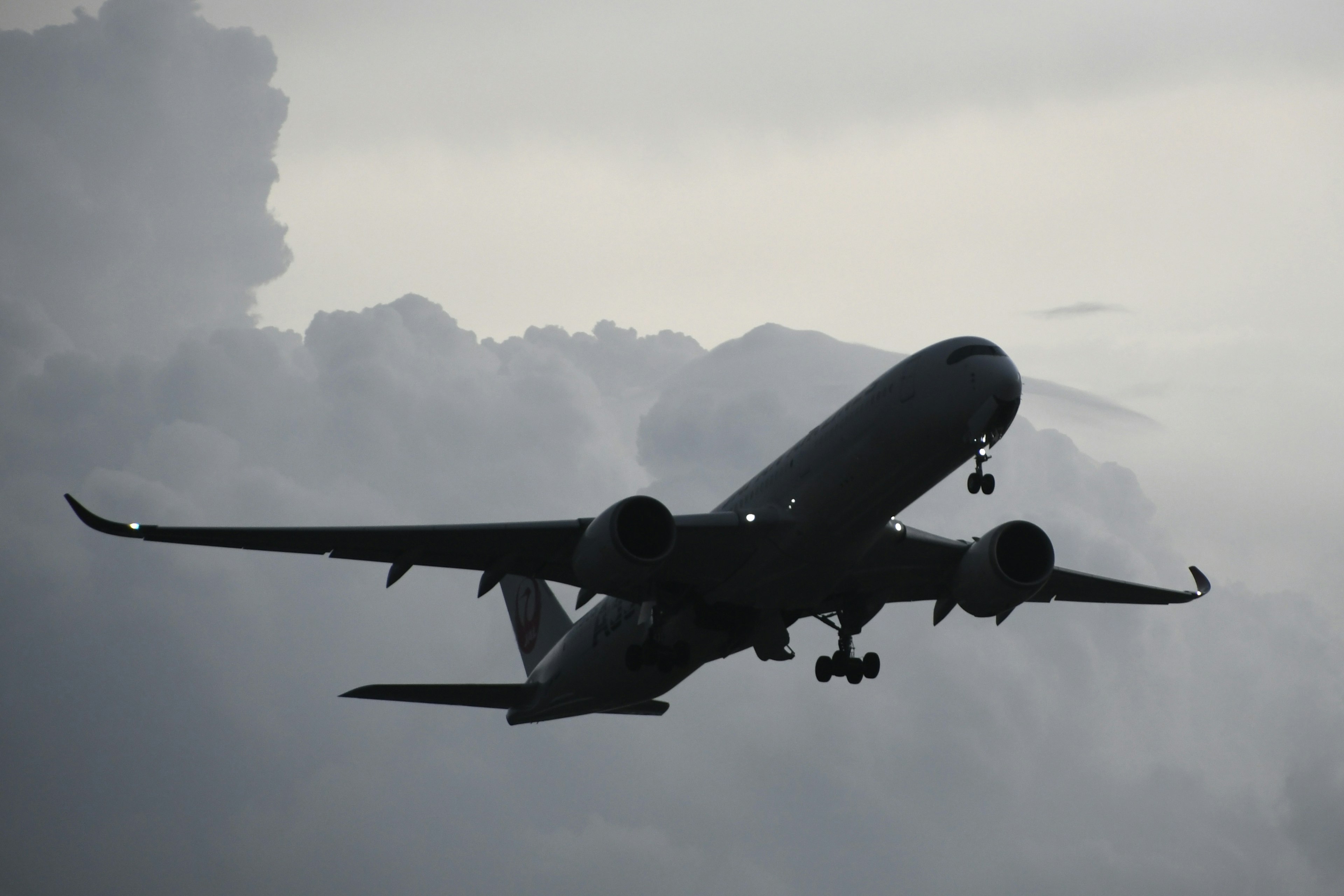 暗い雲の中を飛行する航空機のシルエット