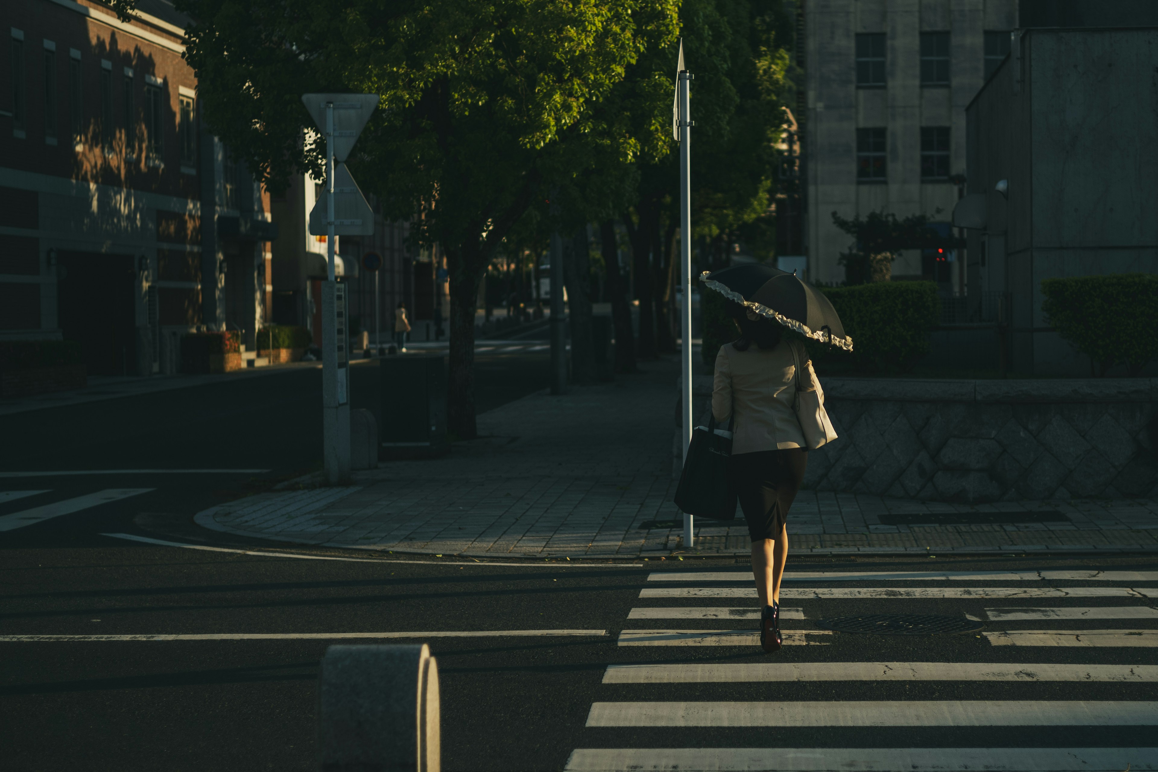 夕方の街角で傘を持って歩く女性のシルエット