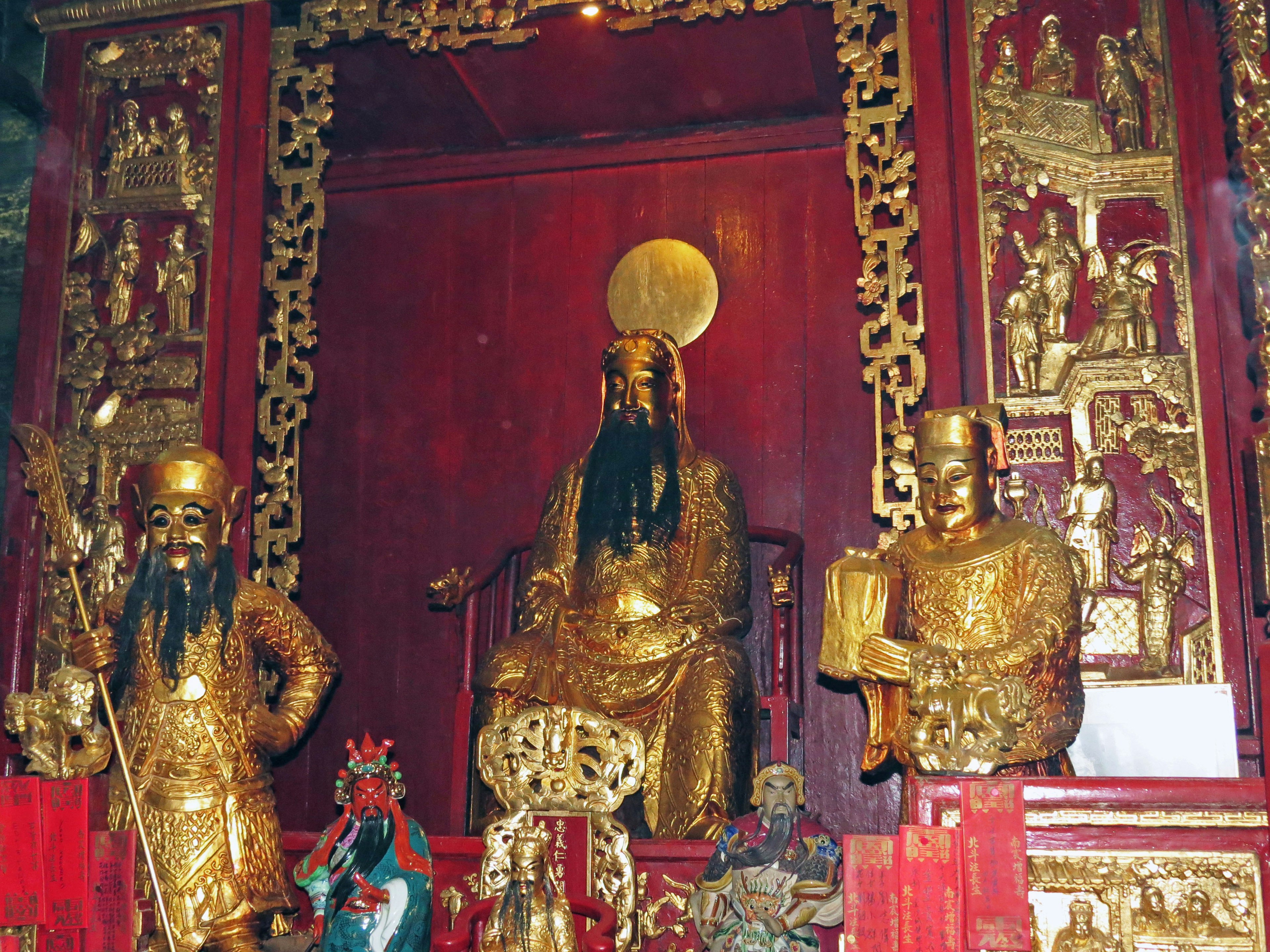 Intérieur d'un temple avec des statues dorées sur un fond rouge