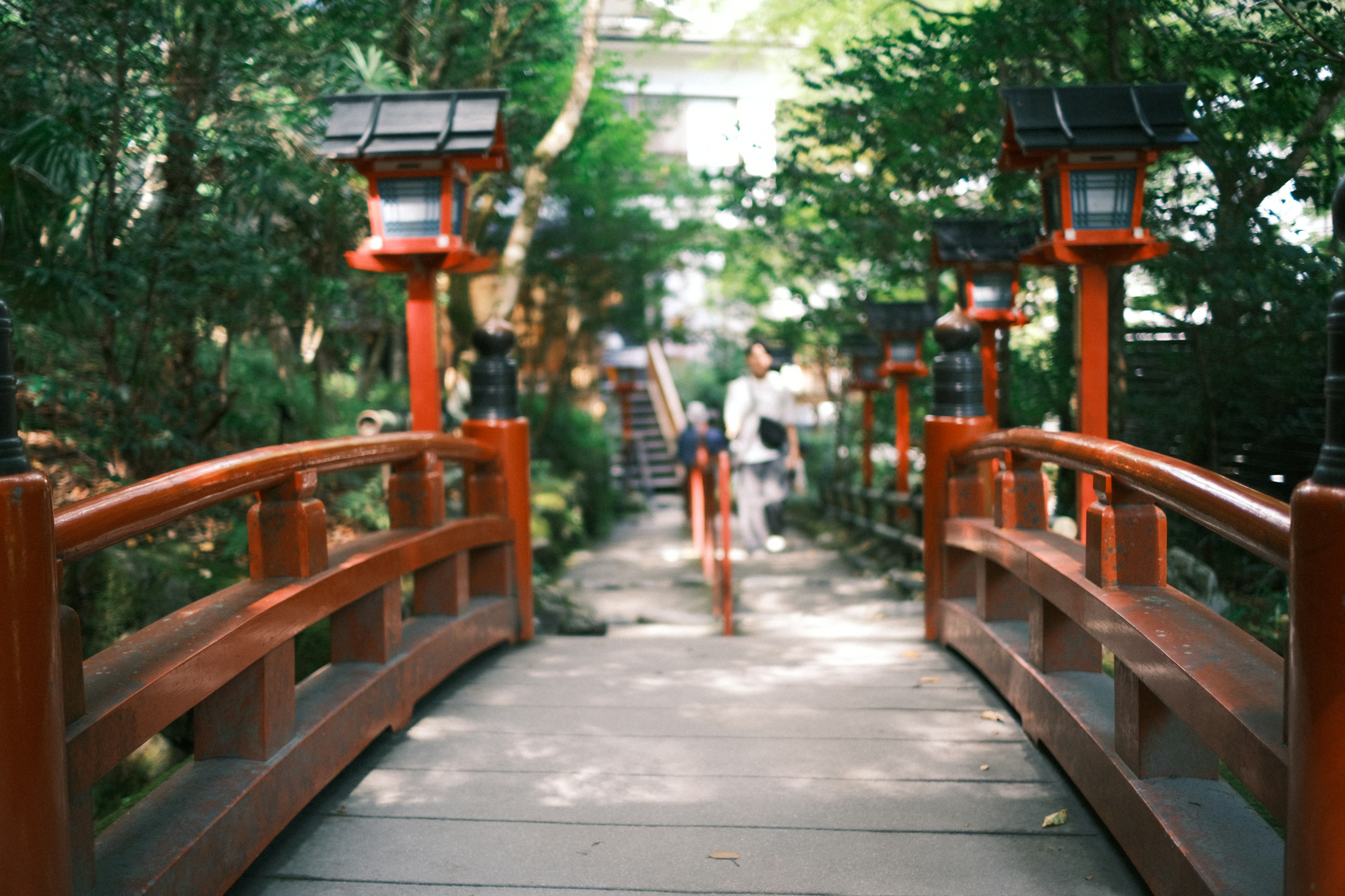 A scenic pathway featuring a red bridge surrounded by lush greenery