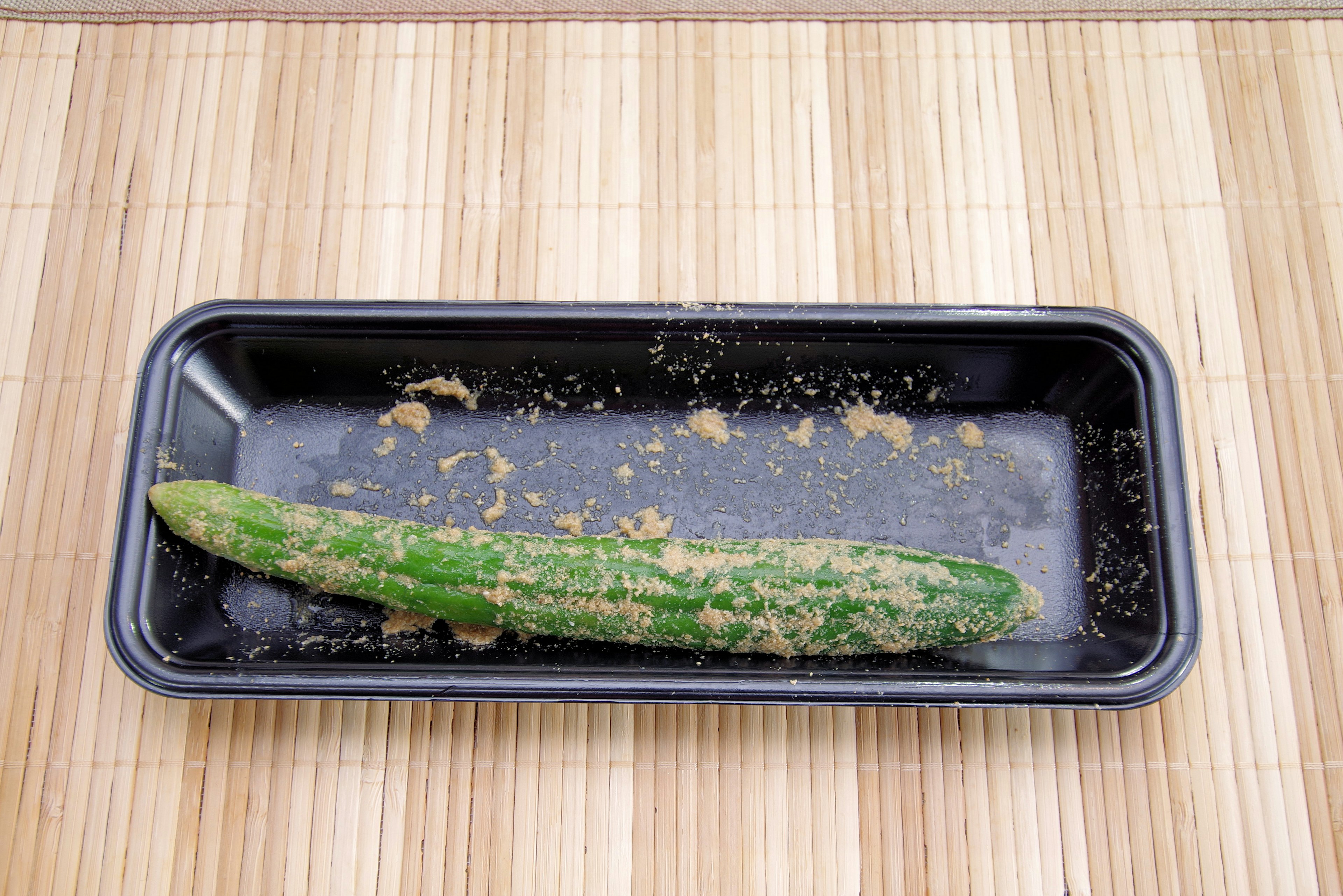 A dirty cucumber in a black tray