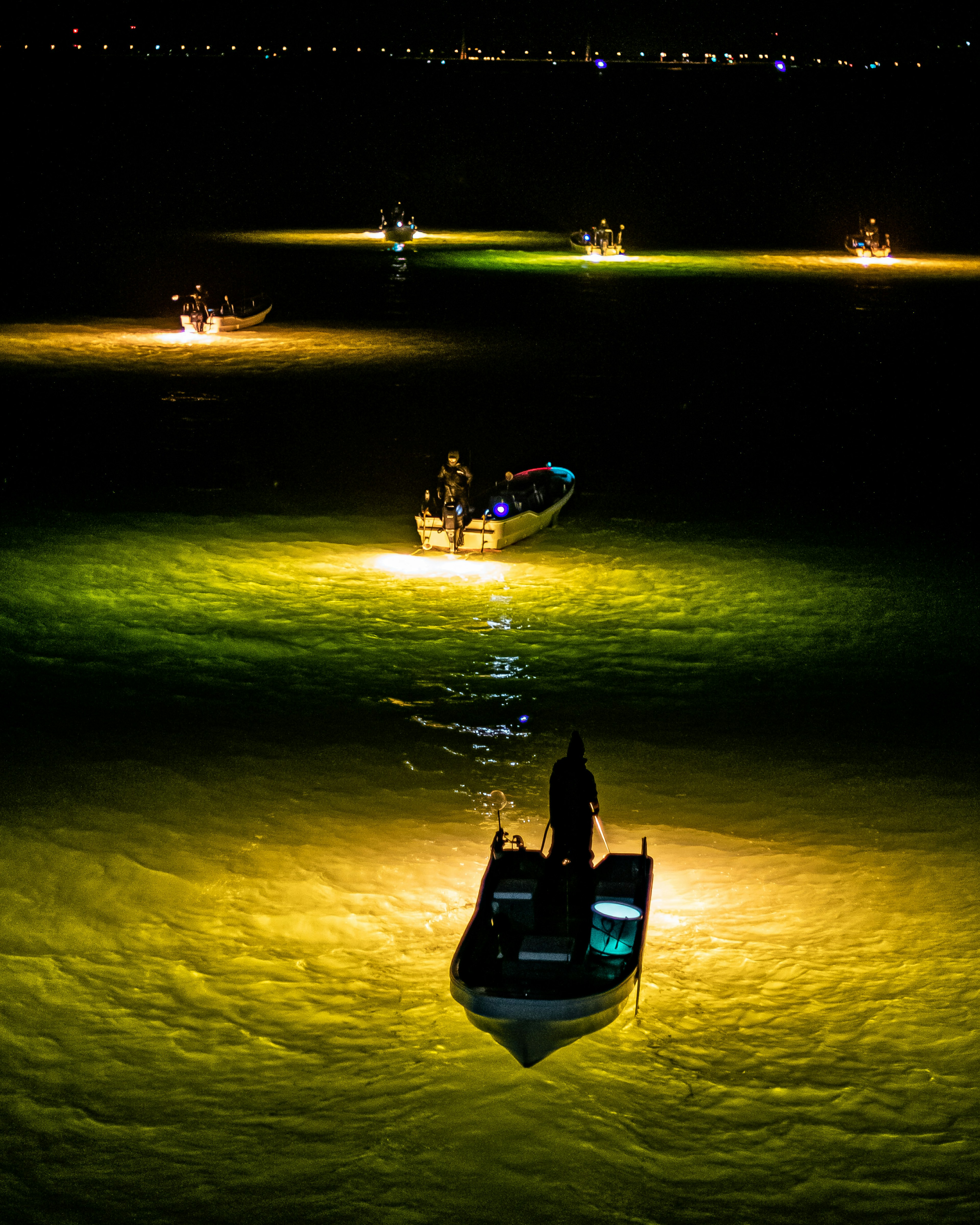 A gathering of fishing boats on the ocean at night lights reflecting on the water