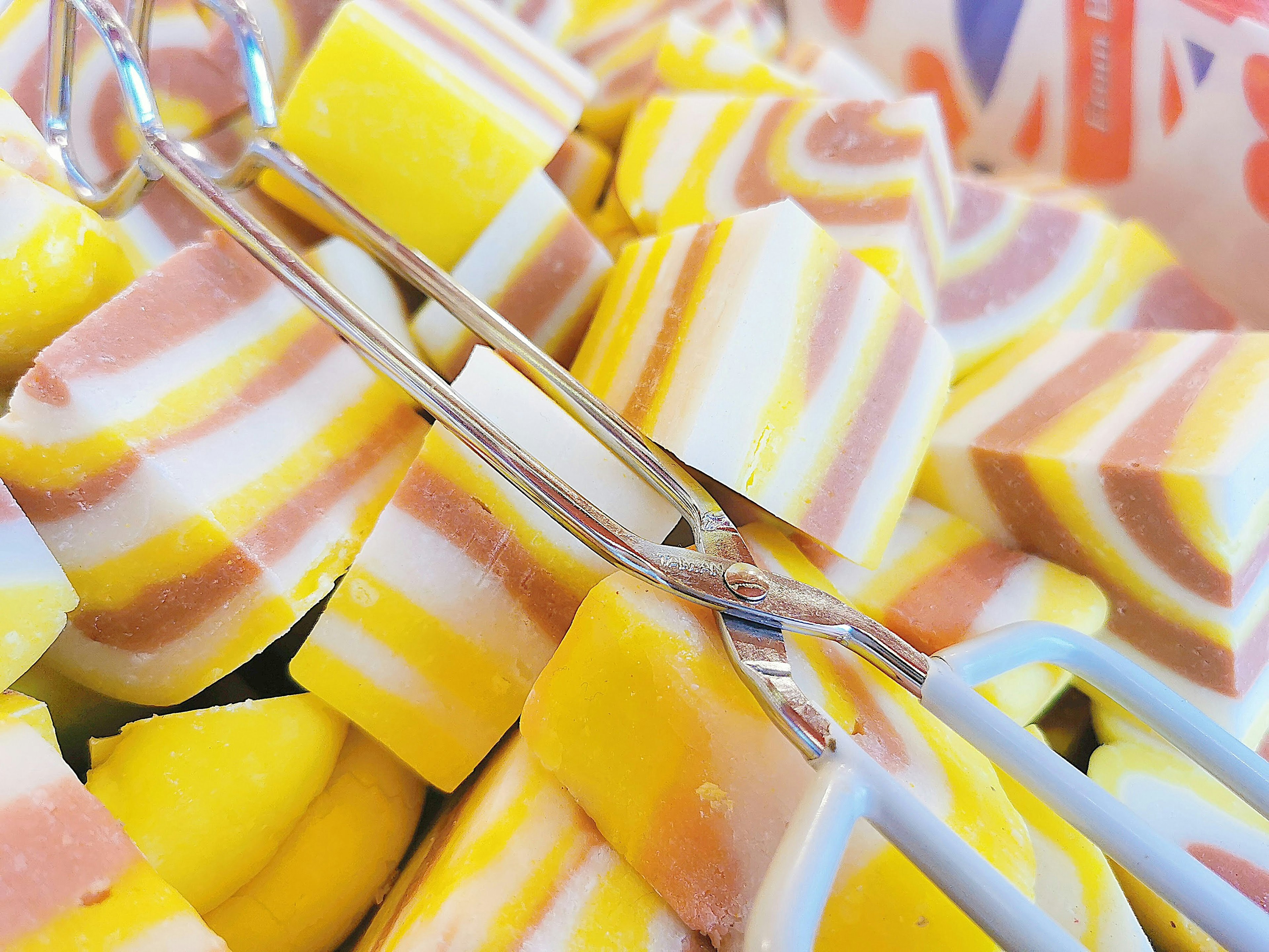 Colorful candies arranged in a basket with silver tongs