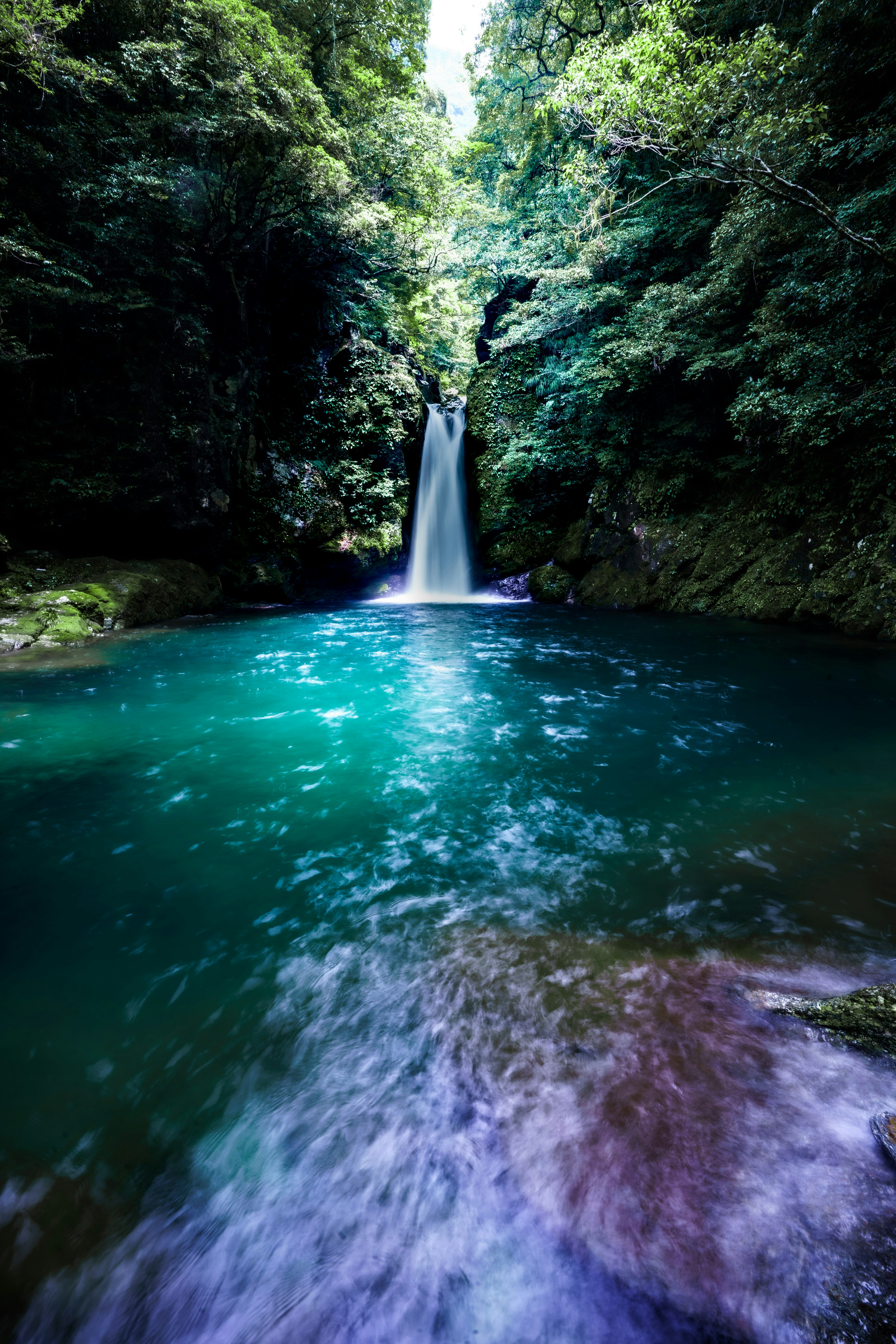 Malersicher Anblick eines Wasserfalls, der in einen türkisfarbenen Pool fällt, umgeben von üppigem Grün